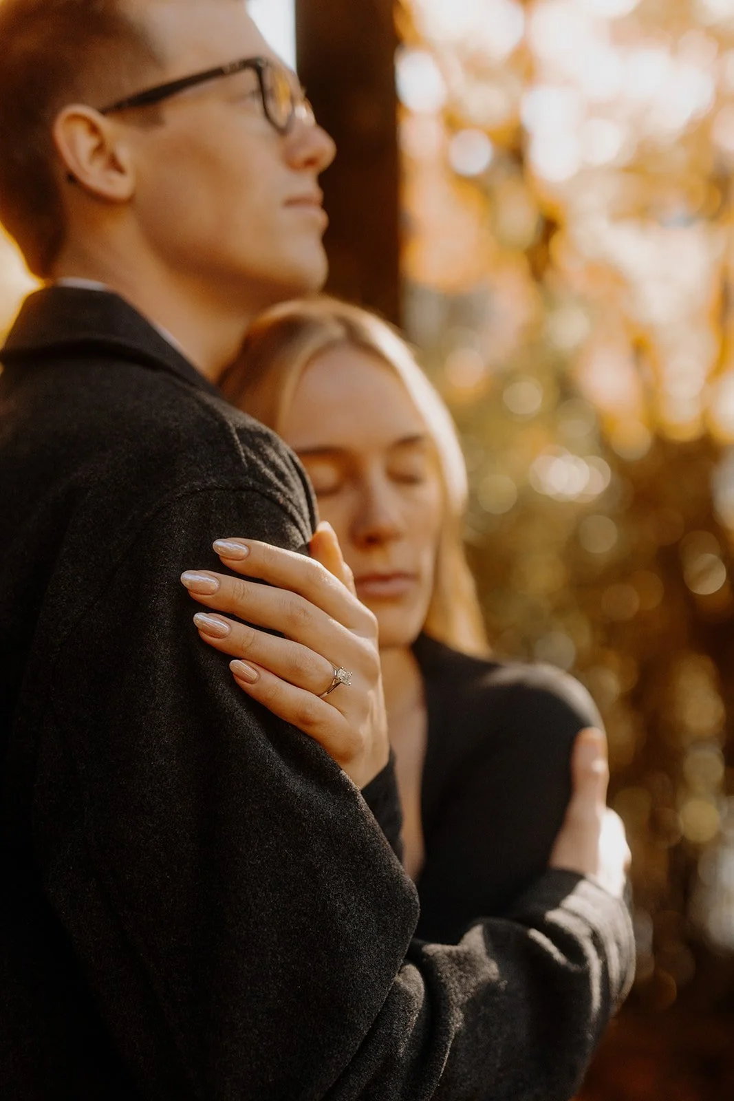 Close-up of a bride's hand resting on her fiance's shoulder showing her new engagement ring in autumn light, Hakone