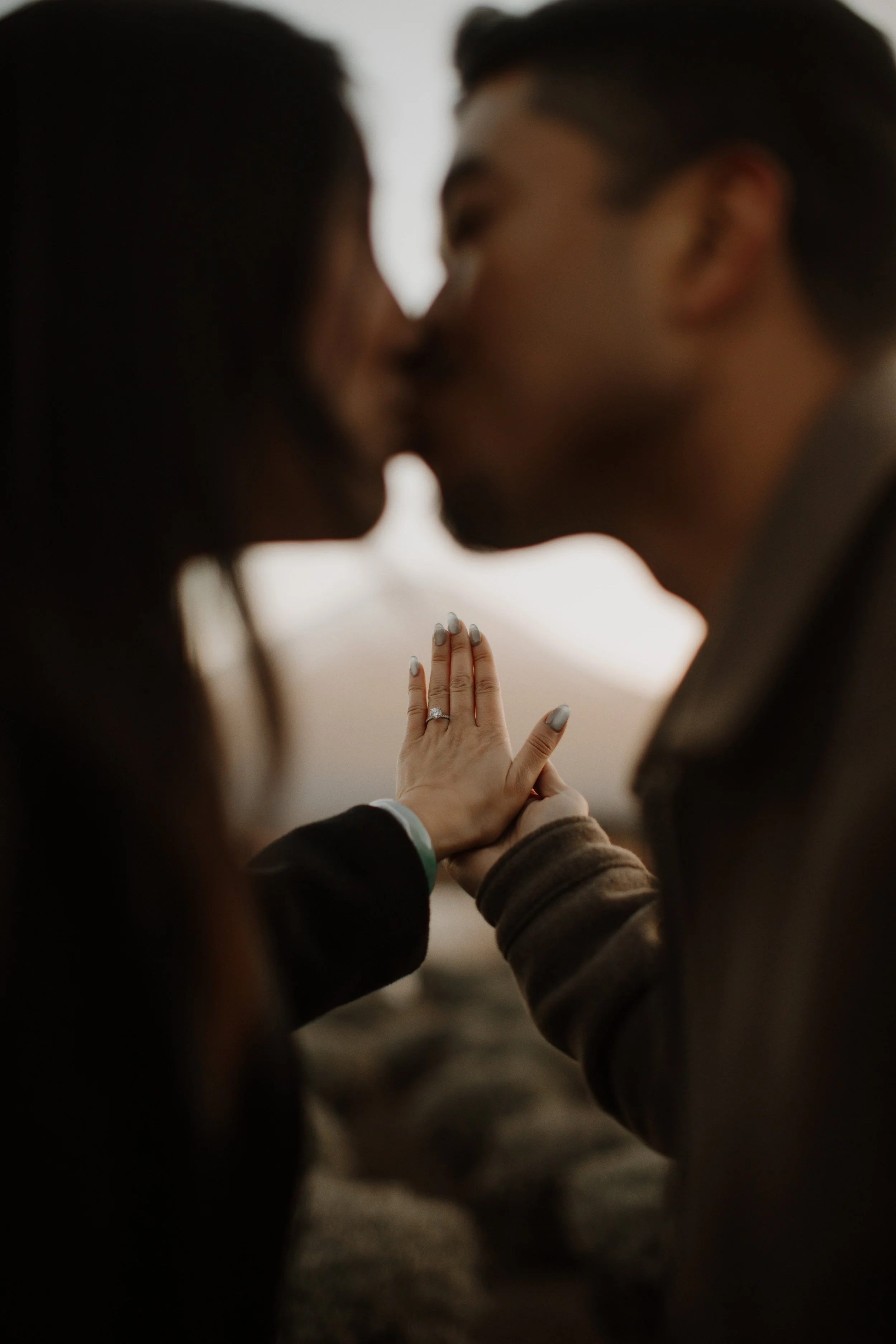 Close-up of engagement ring on bride's hand as newly engaged couple kisses near Mount Fuji
