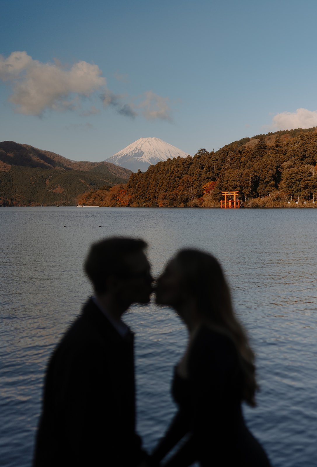 Blurred foreground silhouette of a couple kissing at Lake Ashi with Mount Fuji visible in the distance, Hakone
