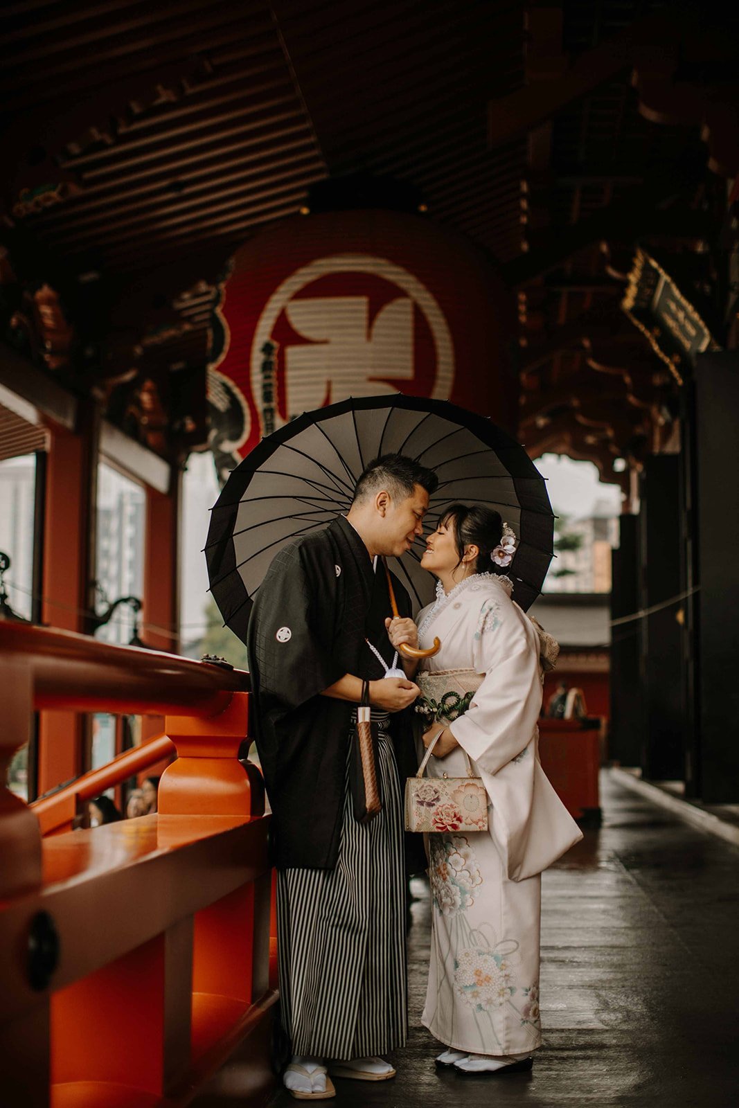 Couple in kimono sharing a moment under a traditional umbrella at Sensoji Temple in Asakusa, Tokyo