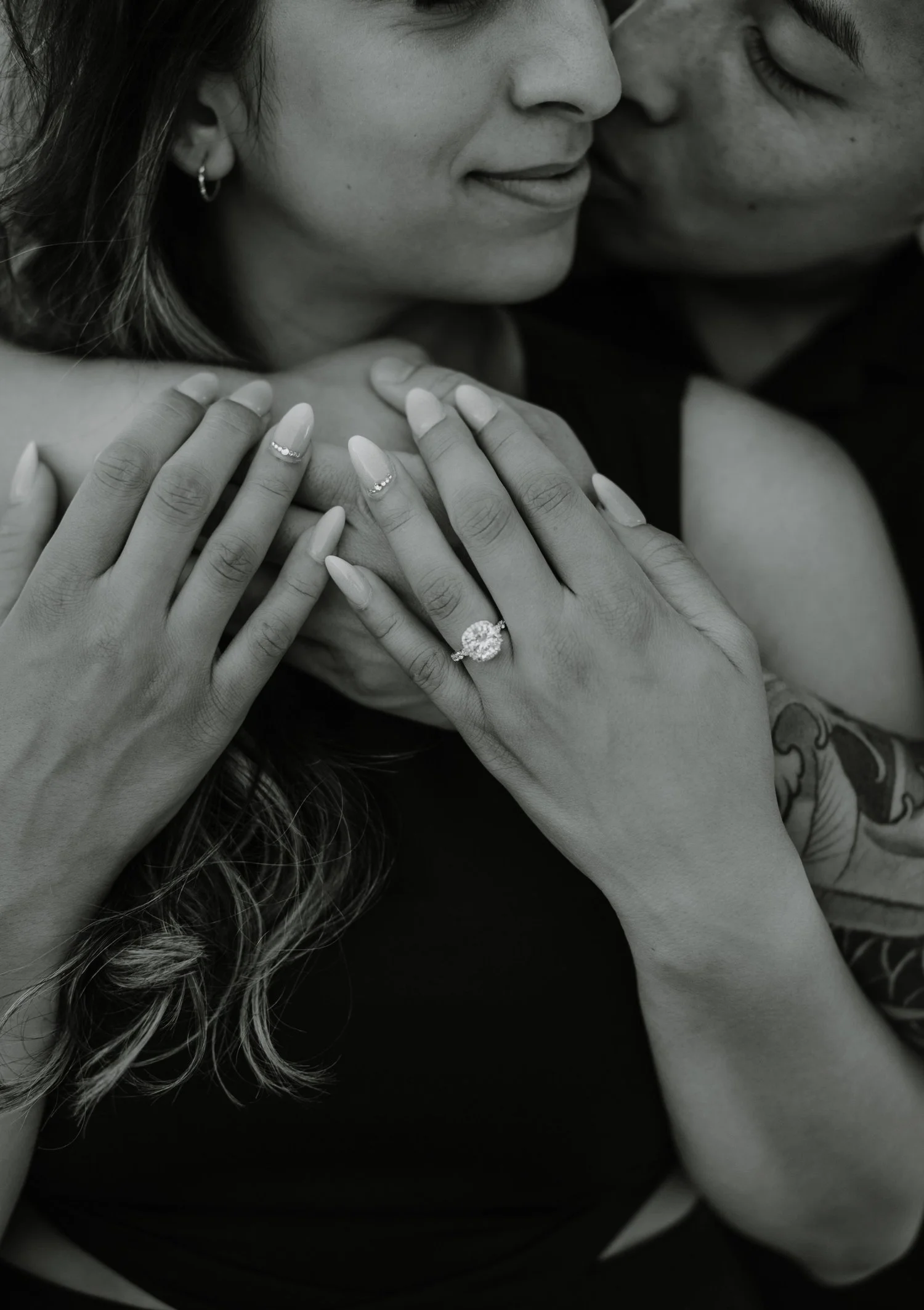 Black and white close-up of a couple's hands showing her new engagement ring