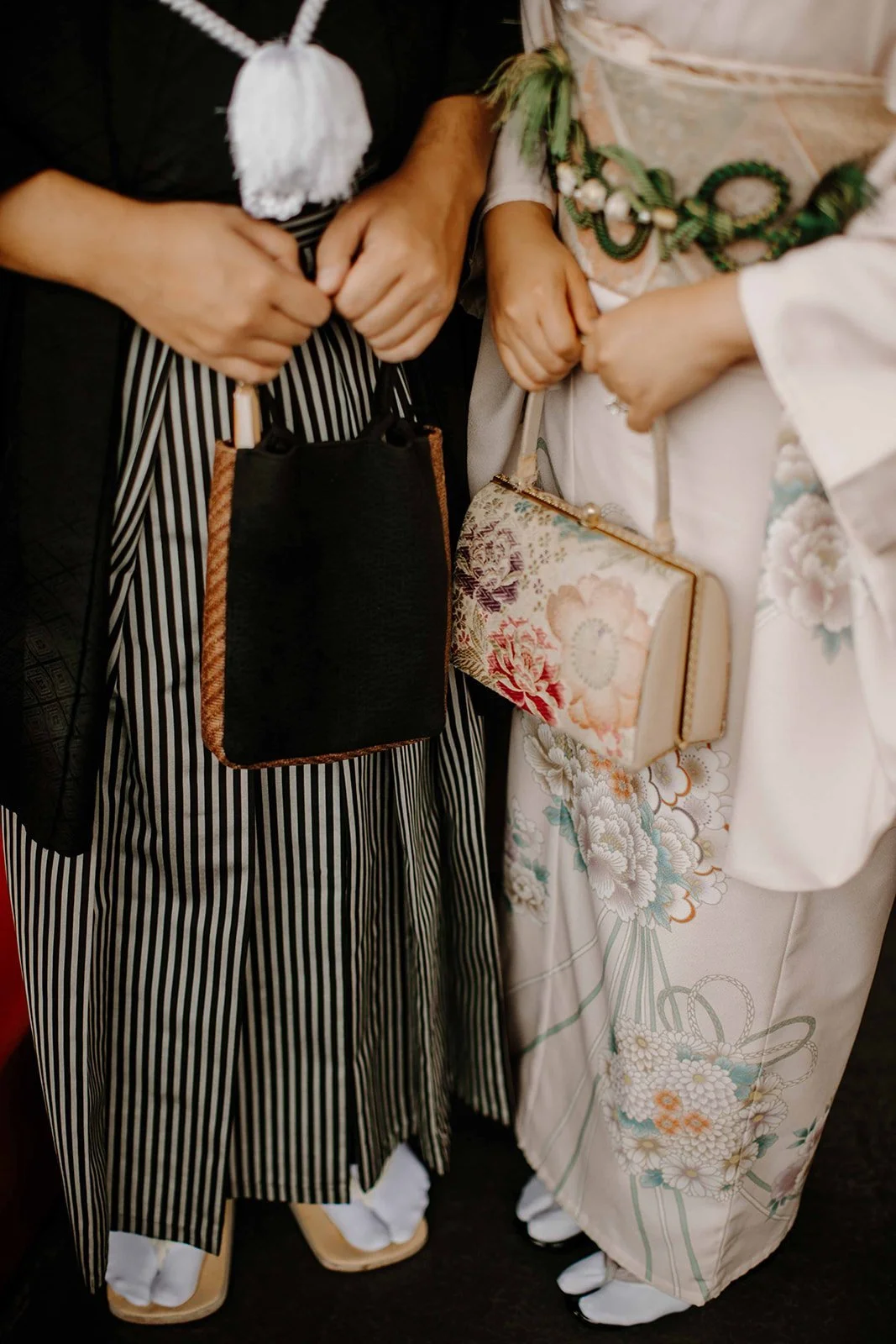 Close-up of a couple's hands holding traditional kimono handbags, showing the fine fabric detail
