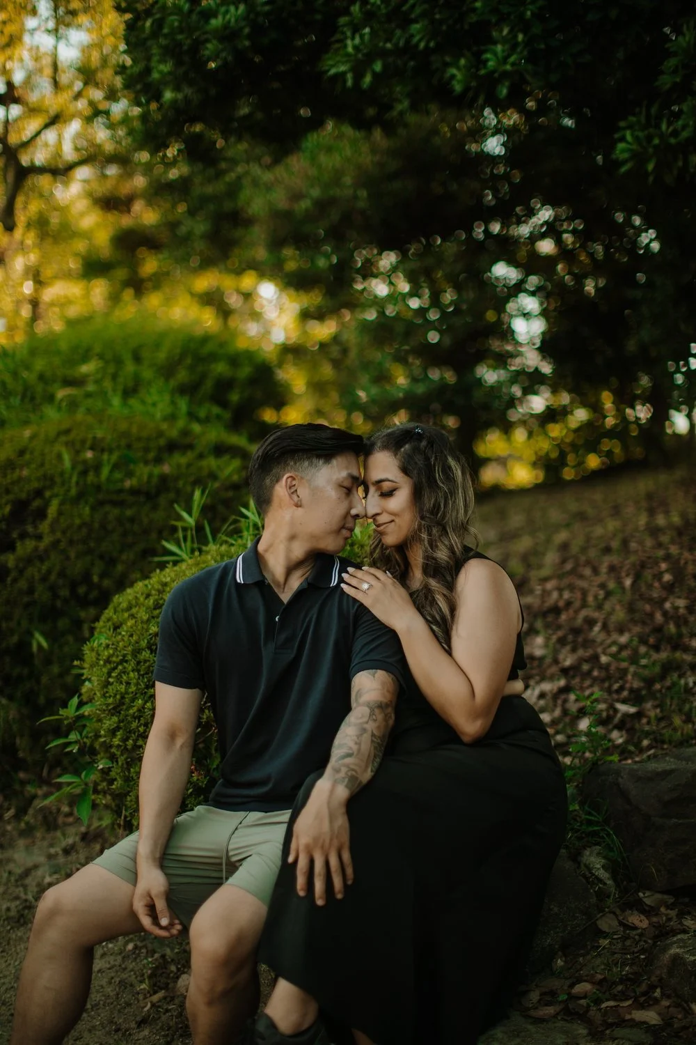 Newly engaged couple sitting together forehead to forehead in the gardens near Osaka Castle at golden hour