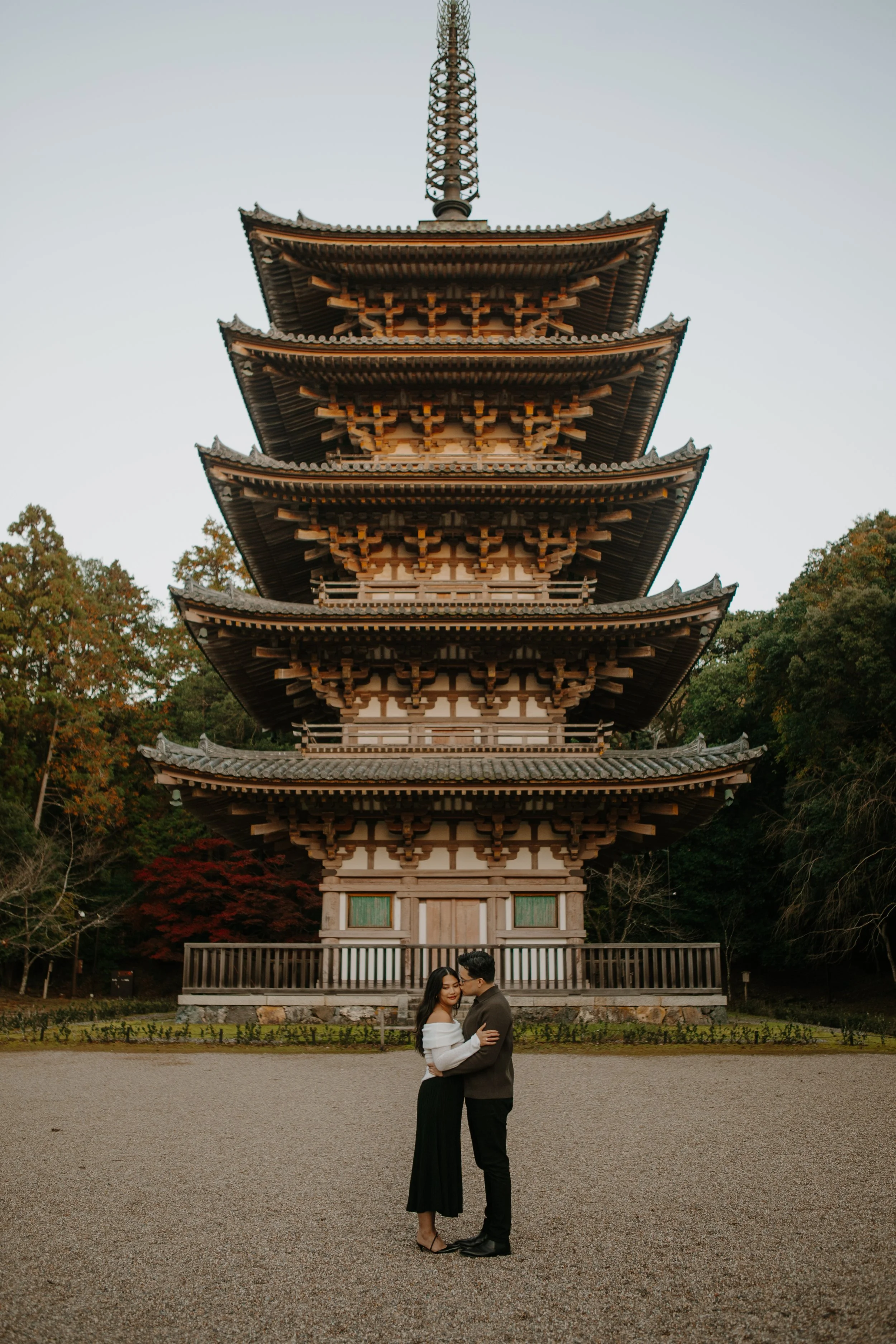 Couple embracing in front of Daigoji Temple's five-story pagoda, one of Kyoto's national treasures.