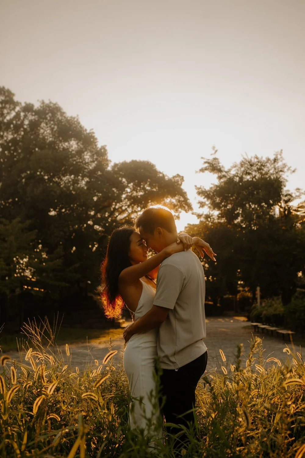 Couple embracing in a sunlit park path near Osaka Castle at sunset