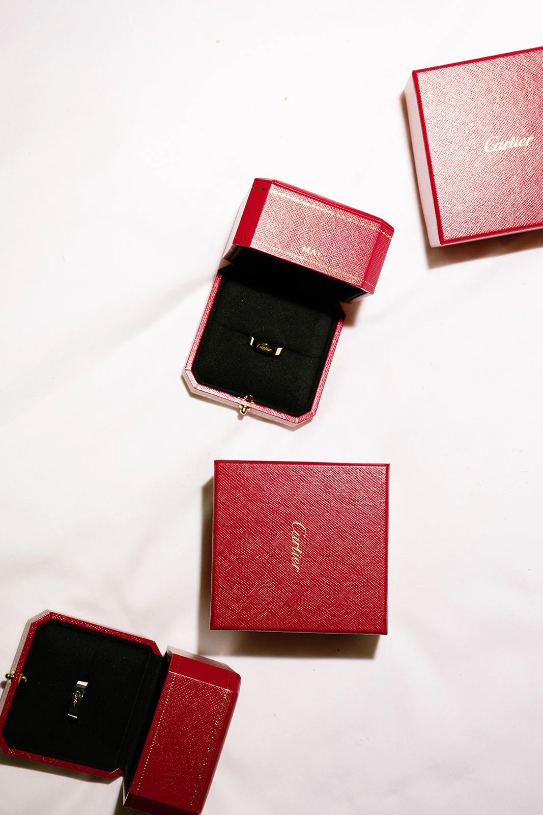 Two Cartier ring boxes open on a table, one holding a wedding band.