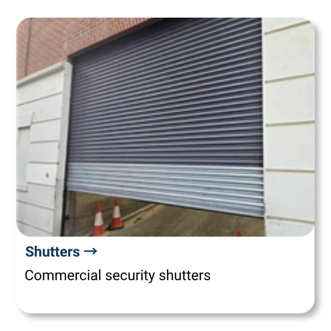 Commercial security shutters partially open, with orange traffic cones nearby.
