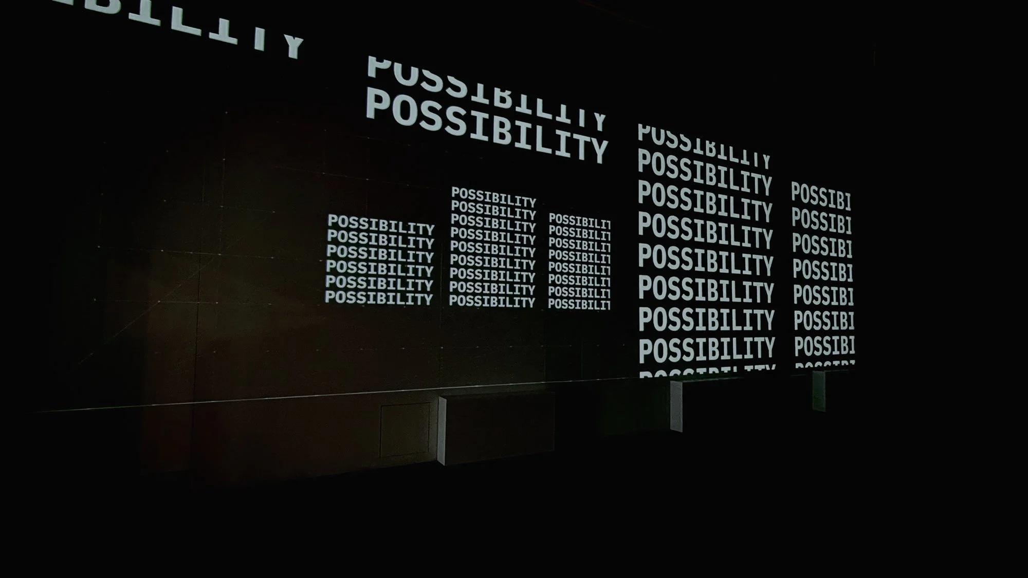 A dark digital display showing the word 'POSSIBILITY' repeatedly in white text with a decreasing size pattern.