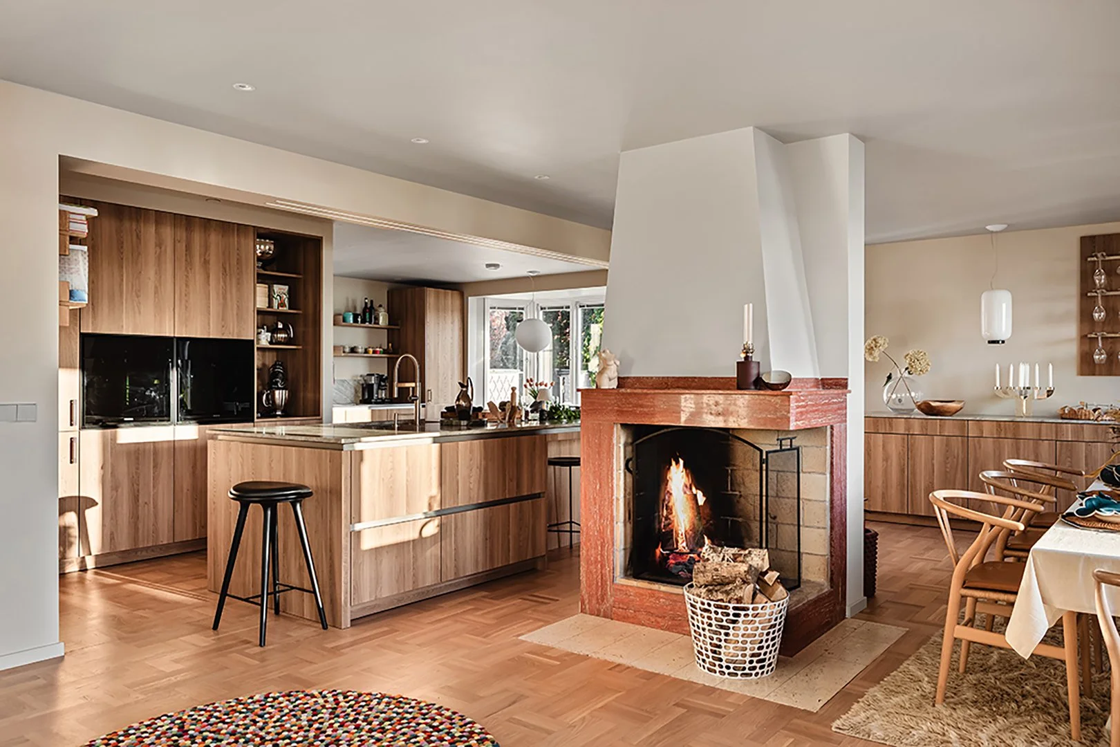 Interiörfoto av ett stort kök med öppen spis. Köket är stilrent i trä med stor köksö.