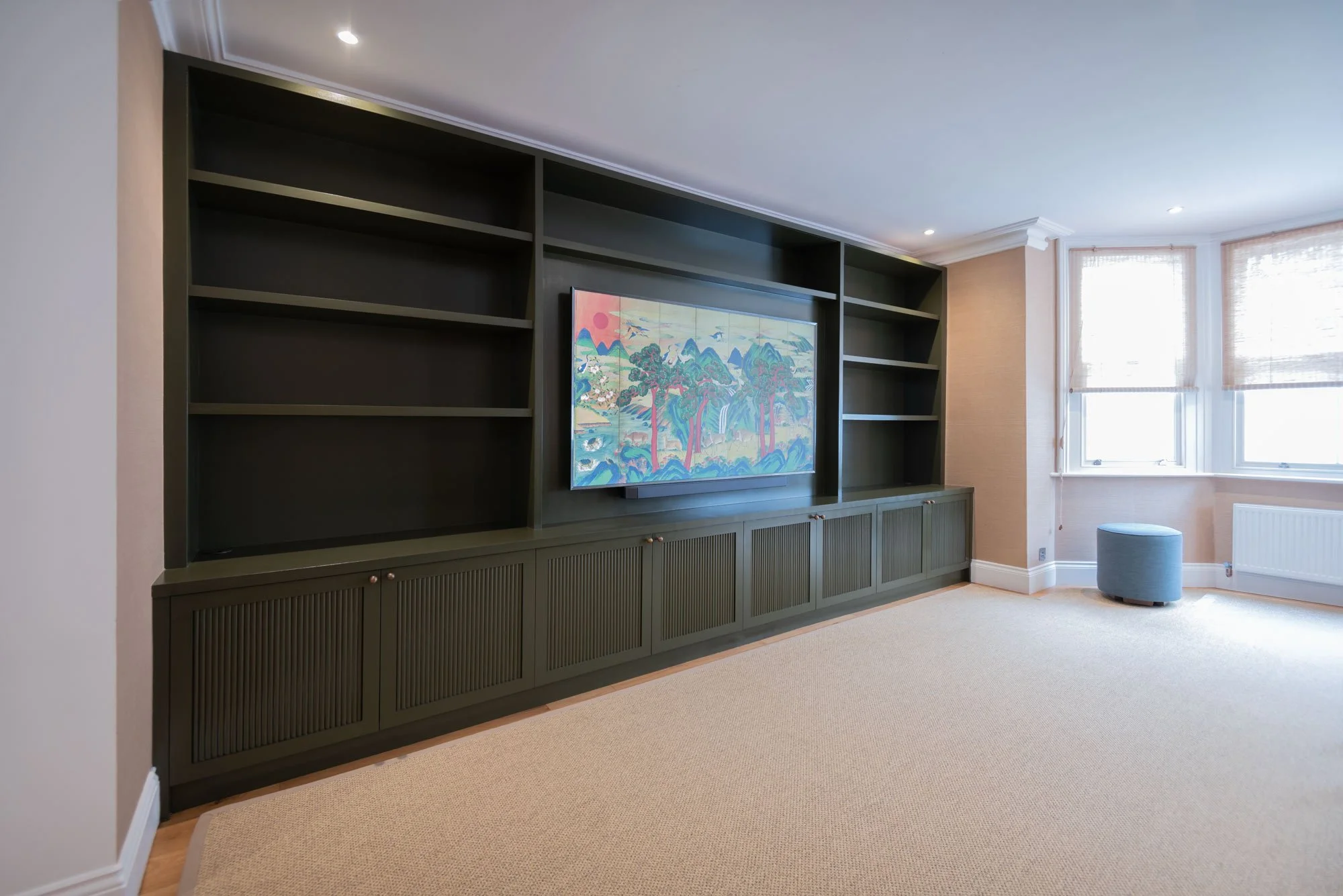 Bespoke media wall in West London W14, floor-to-ceiling joinery with shaker doors and hand painted dark green finish