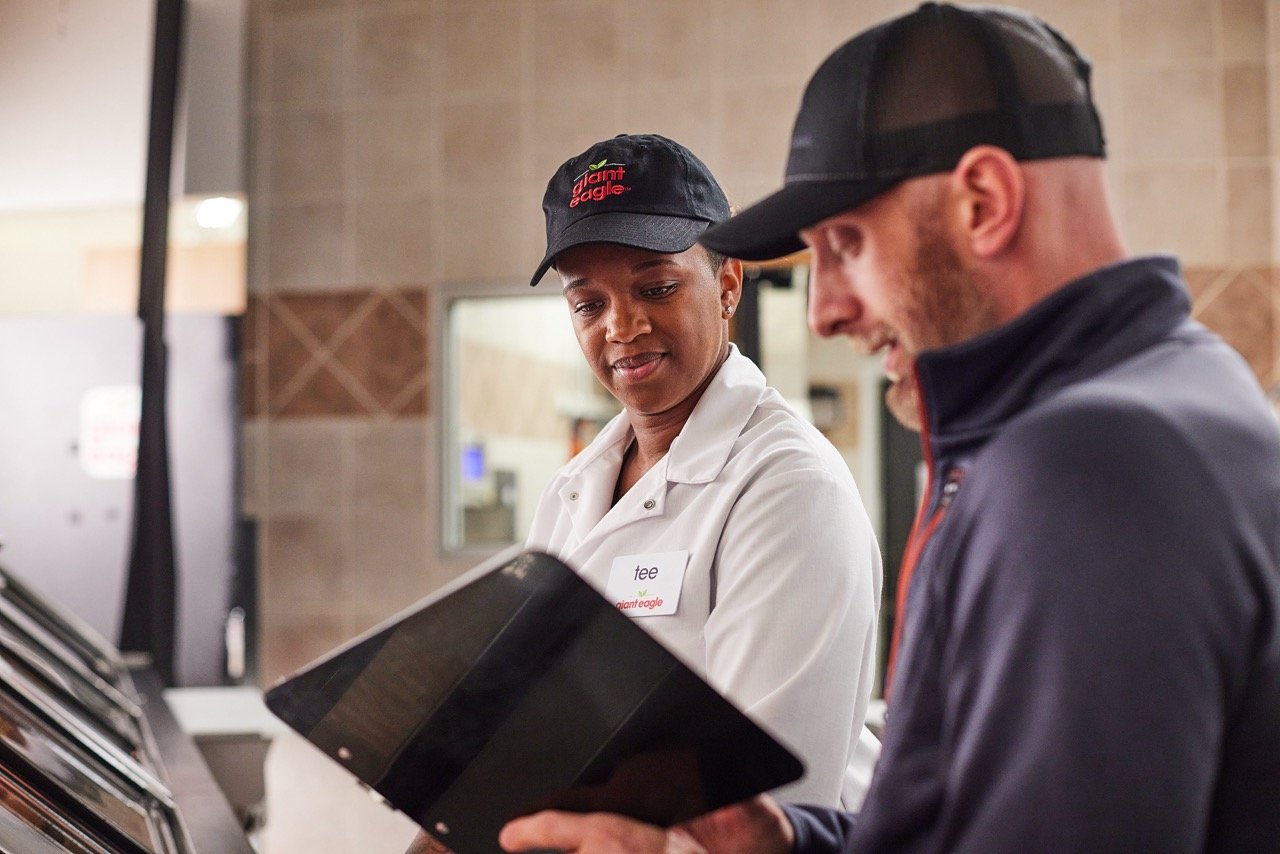 Director and talent on set in a store environment, one reading from a clipboard and the other looking on.