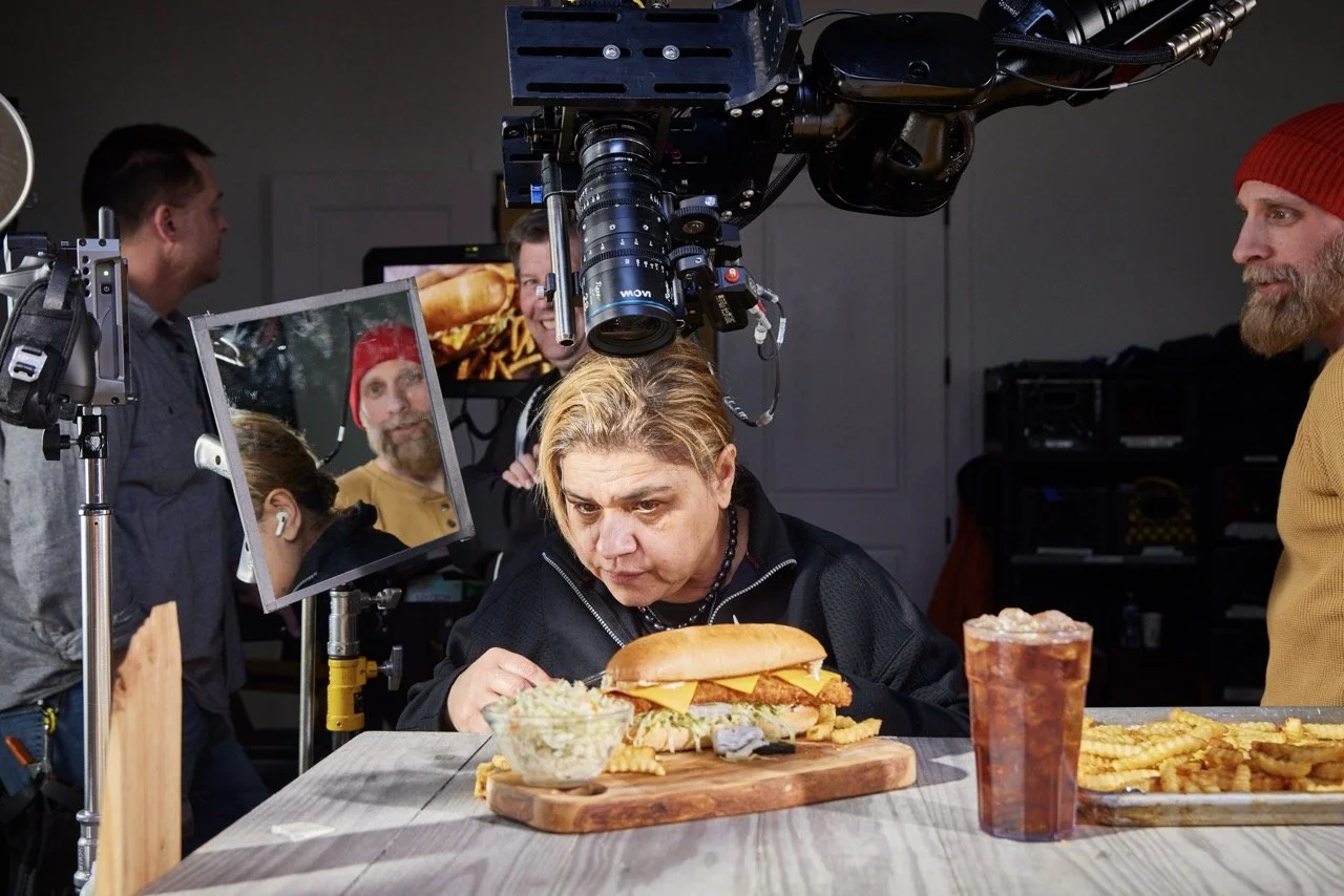 Food Stylist perfects her work in studio setting with Pittsburgh commercial director looking on, and filming equipment all around for video production.
