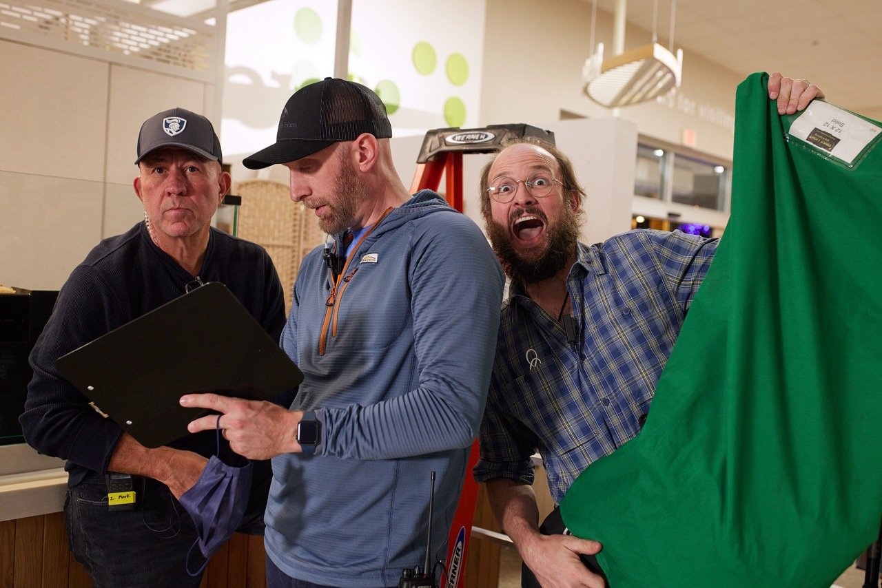 Director and assistant director talking on set during TV commercial production. PLUS Grip.