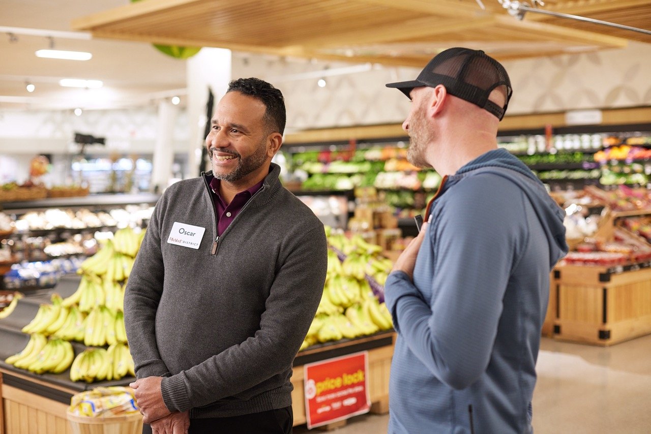 Director and talent talking in a grocery store produce section during TV commercial production.