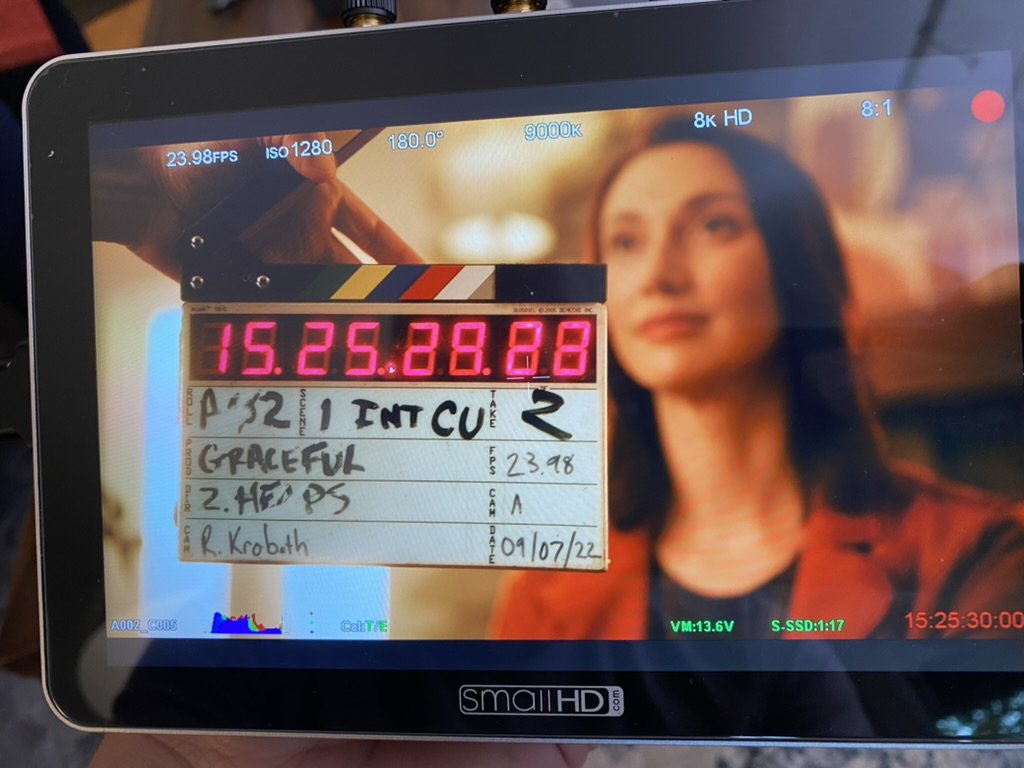 Close-up of a film set display showing a clapperboard on a monitor with a blurred background.