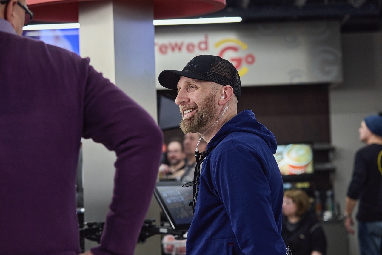 Behind-the-scenes with director and talent on commercial film set.