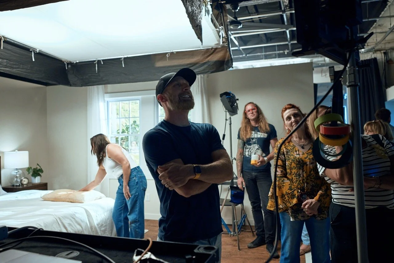 Behind the scenes on a commercial photo shoot in studio with a custom built bedroom film and video set.  Pittsburgh commercial director watches the action.