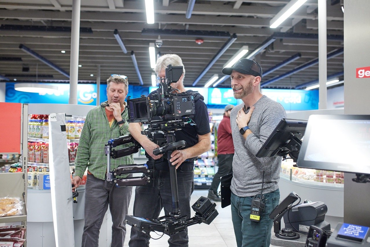 Film crew operating a camera on a stabilizer rig in a grocery store.