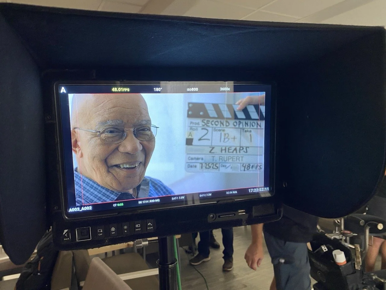 A smiling actor, seen through a camera's monitor during filming of Pittsburgh area TV commercial video production.