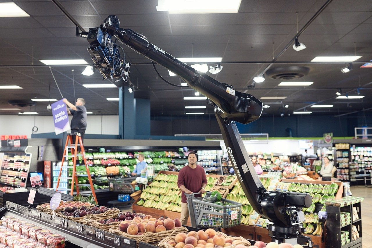 A large robotic camera arm in a grocery store filming the produce section.