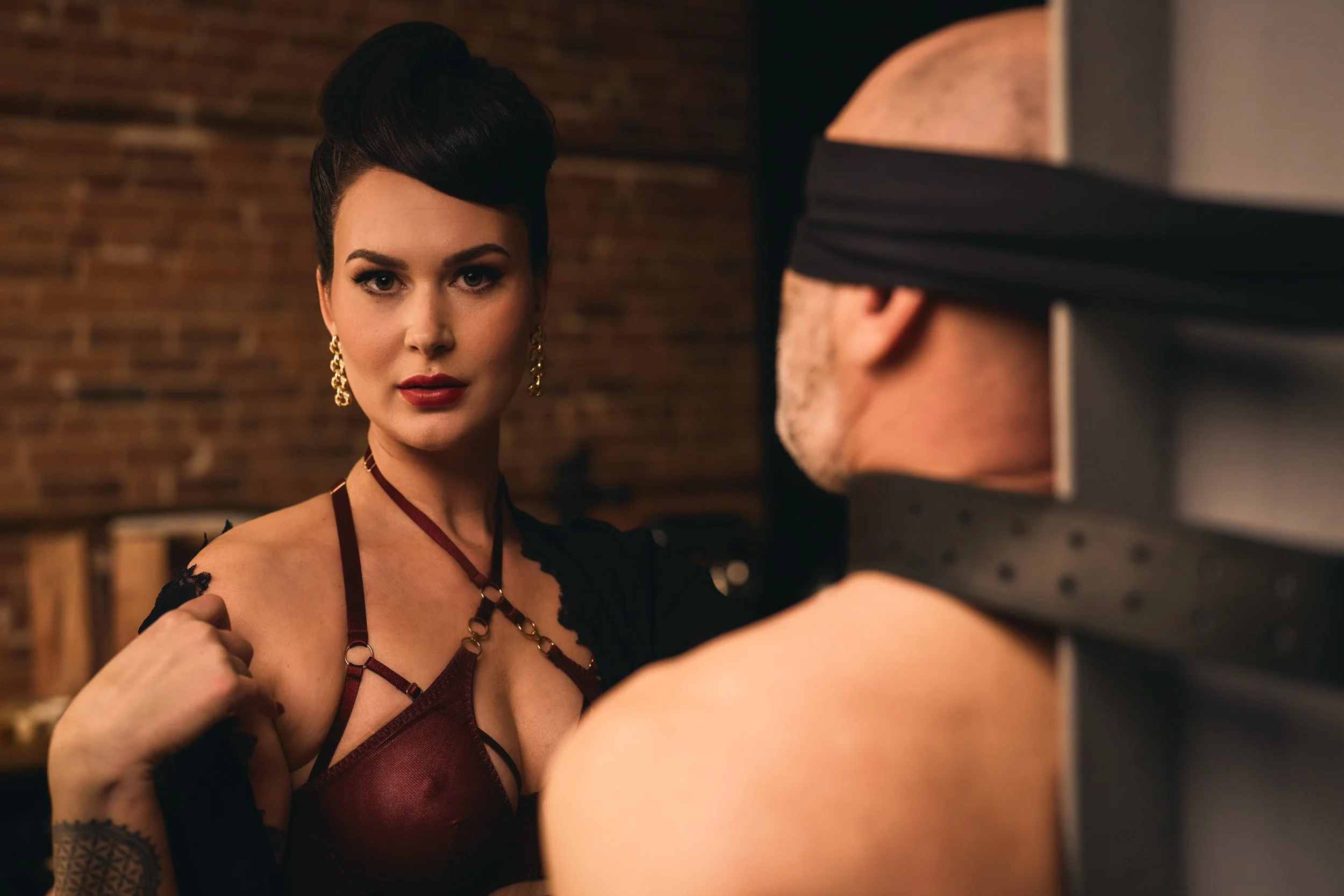 Portrait of a woman in a studio setting, engaging with another person partially visible in the foreground