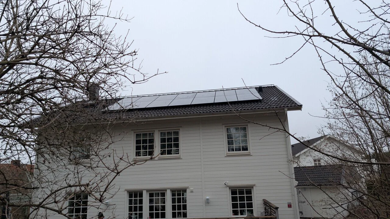 En vit och svart hus med solceller på taket. Novamontage. Nova solpaneler.