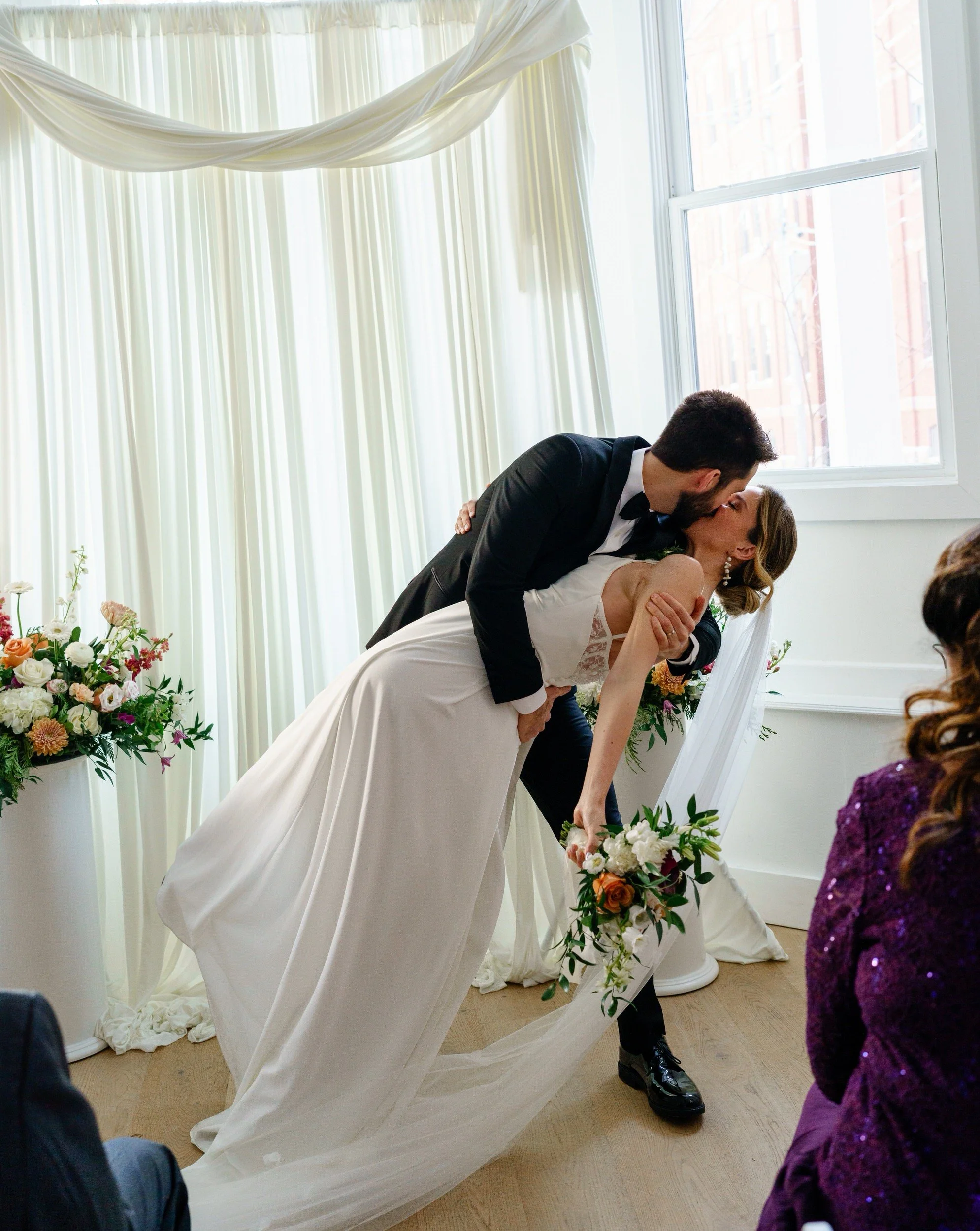 A person dipping their partner and kissing them during their wedding ceremony