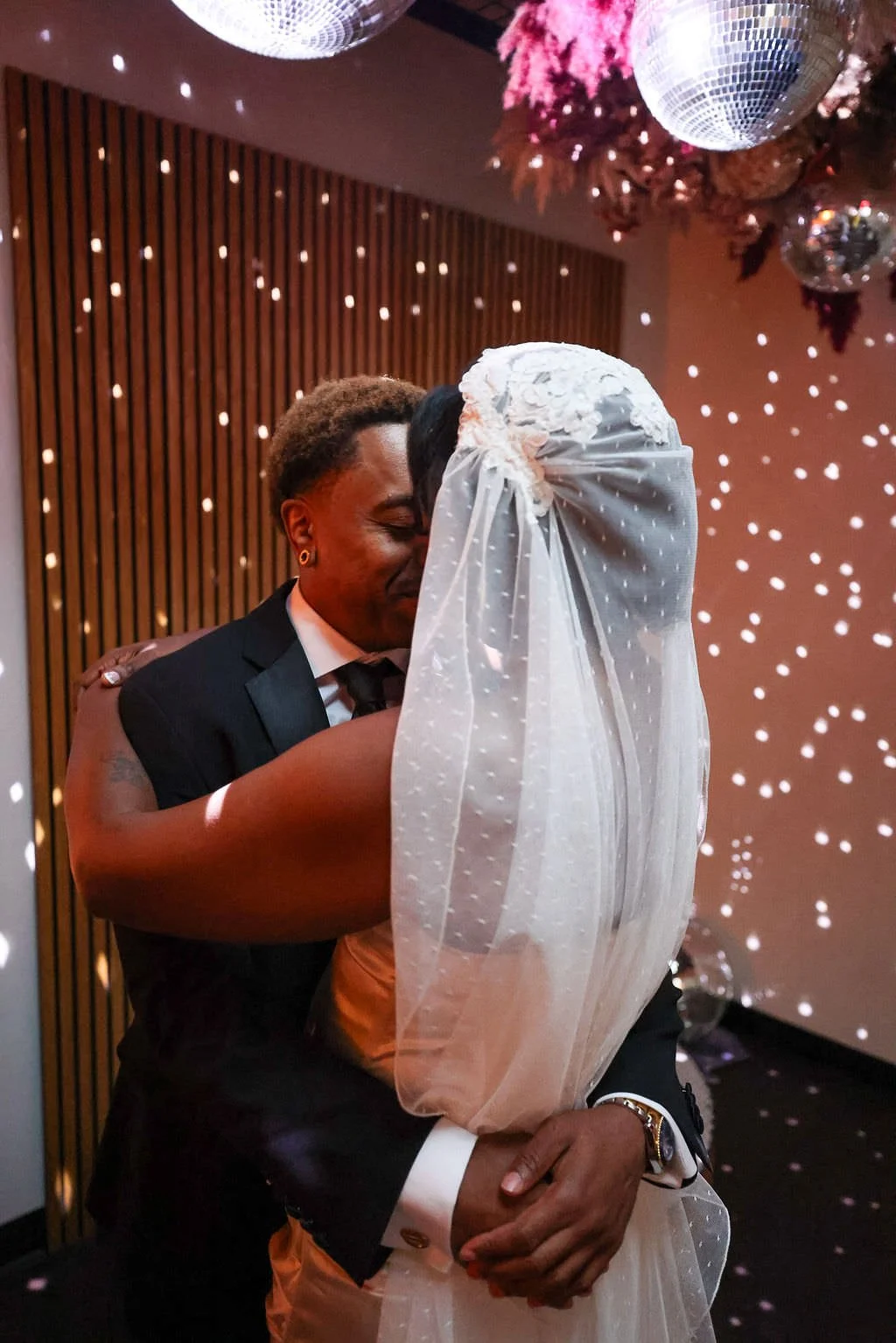 Newlyweds dancing closely together under disco lights 