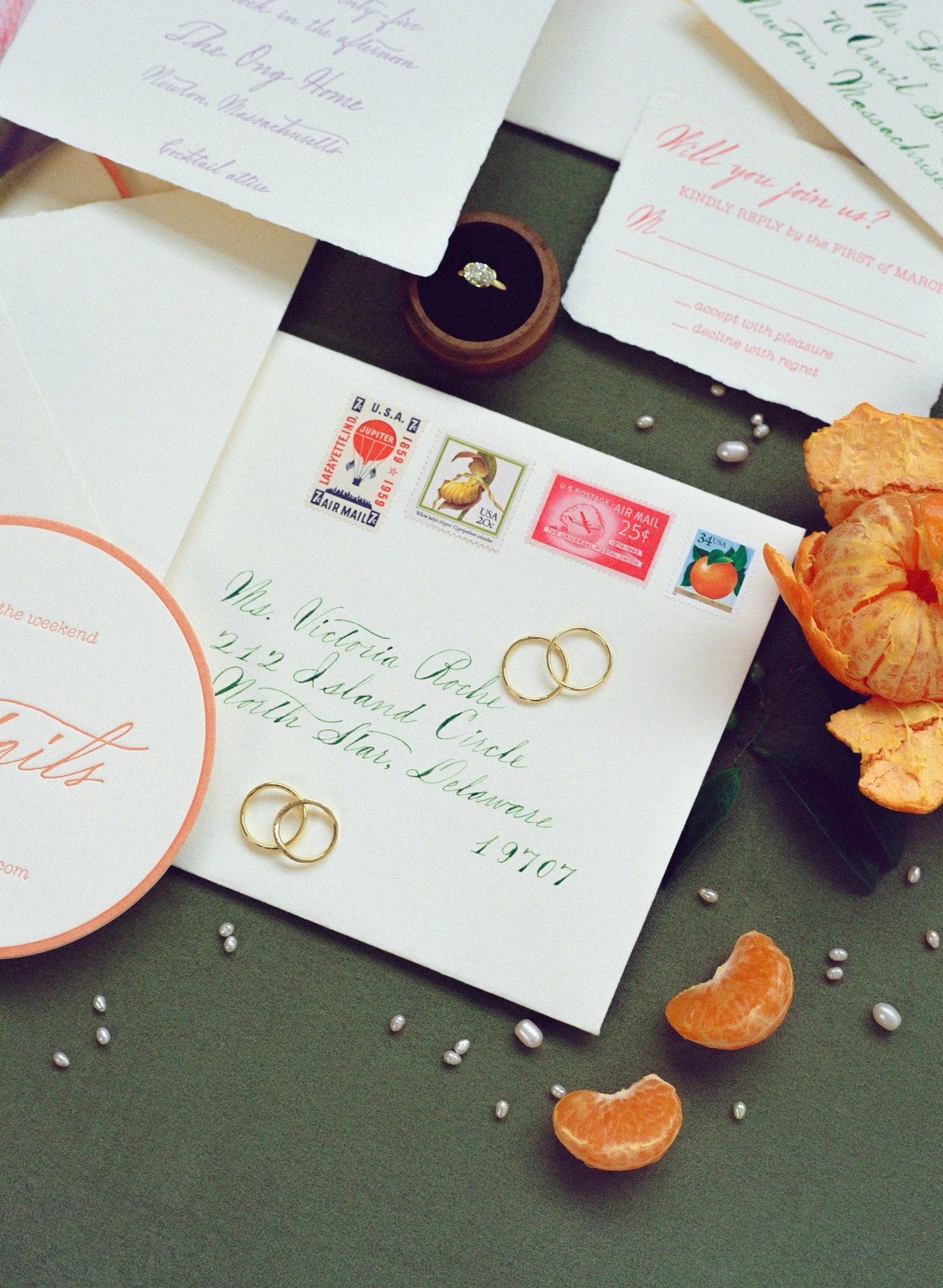  Wedding rings laid out and around custom wedding invitations and envelopes 