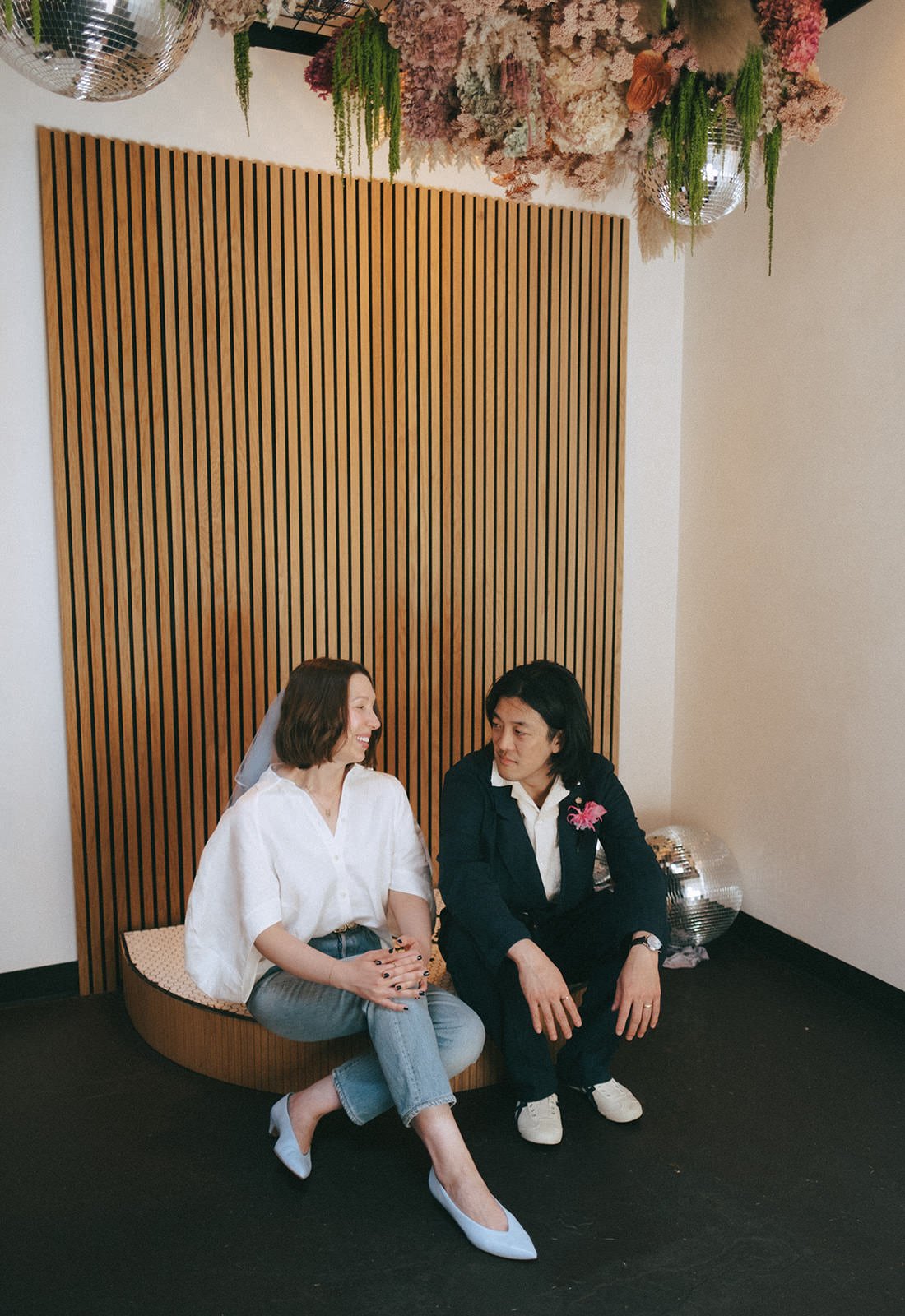 Newlyweds sitting together on a small platform as they laugh