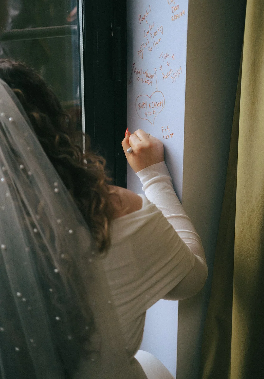  A newlywed signing a wall with their name and wedding date 