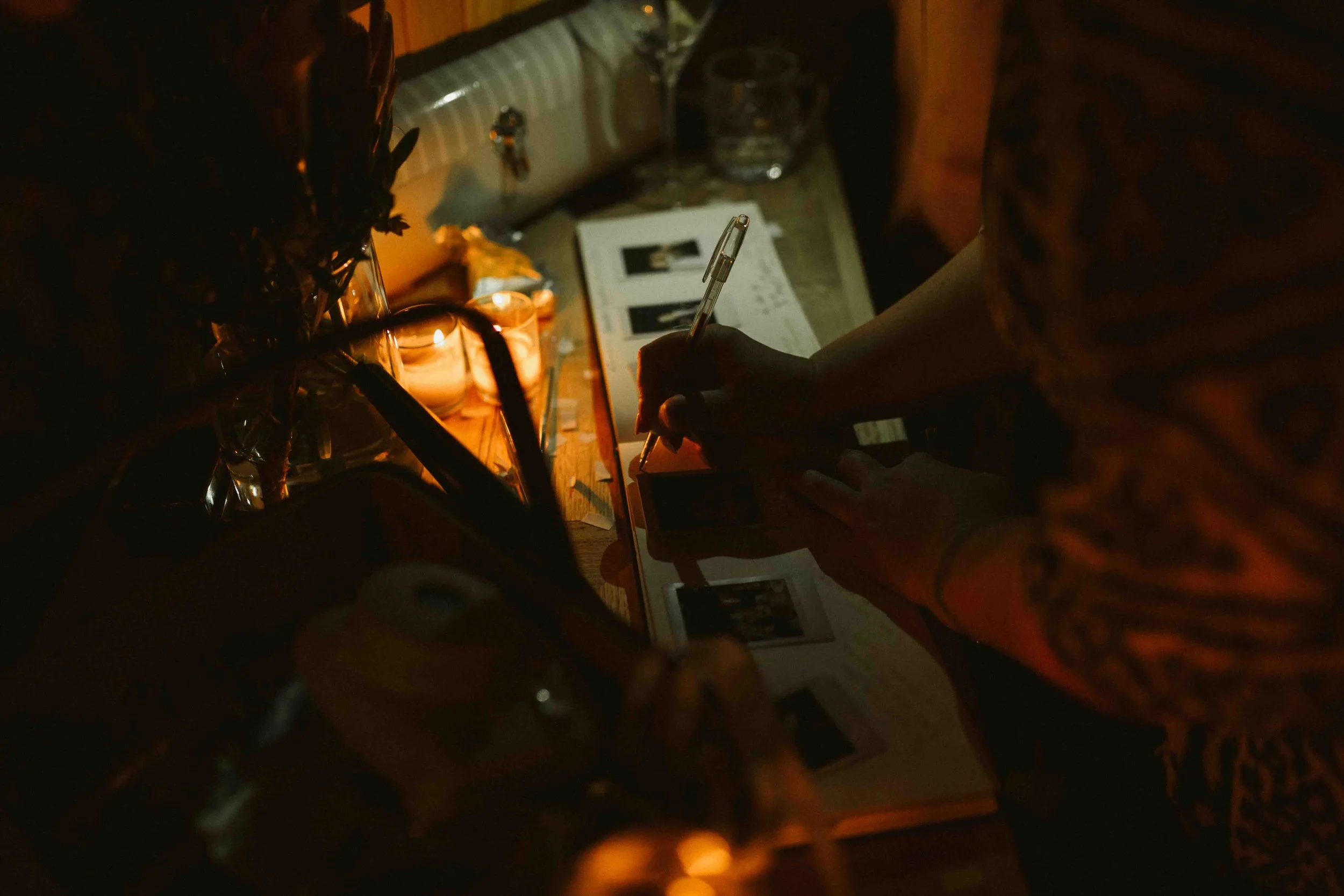  Wedding guests signing a reception book with polaroid images in it  