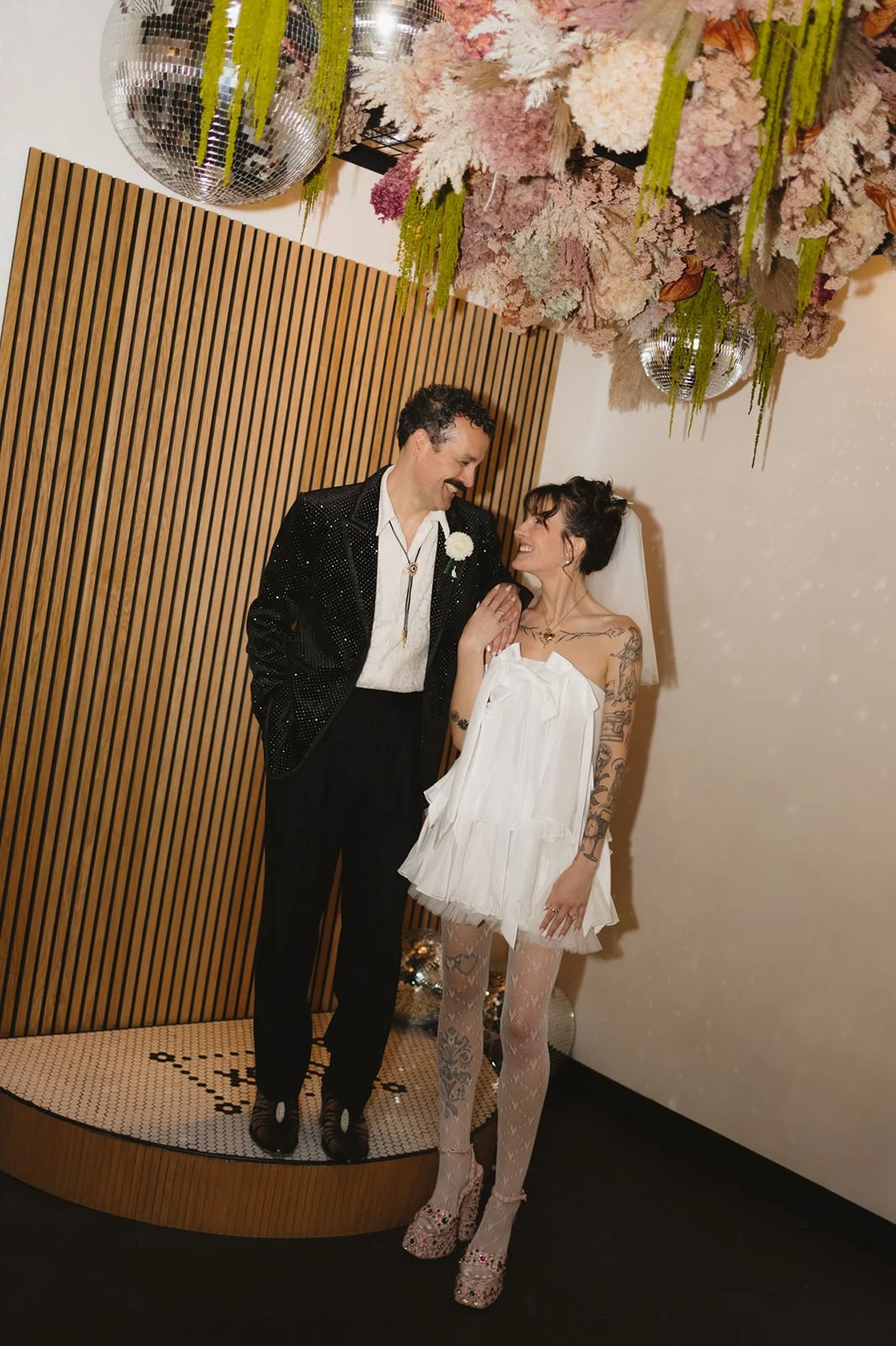 Newlyweds smiling as they stand on and next to a small ceremony platform