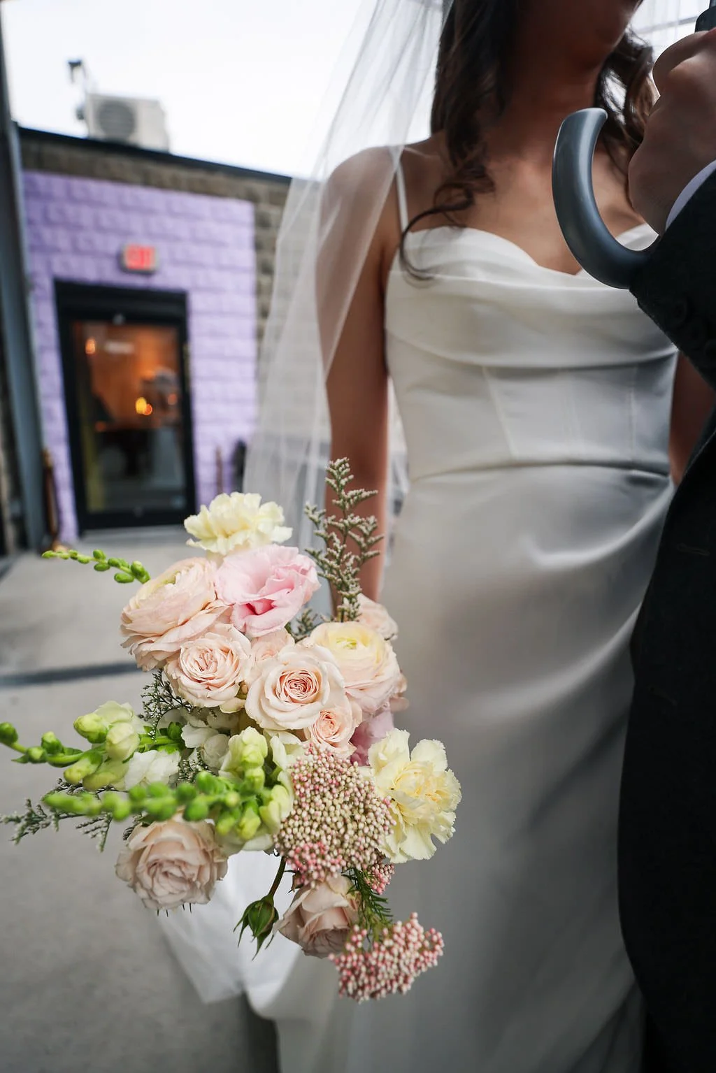  A close up of a newlywed in a wedding dress holding a bouquet of flowers 