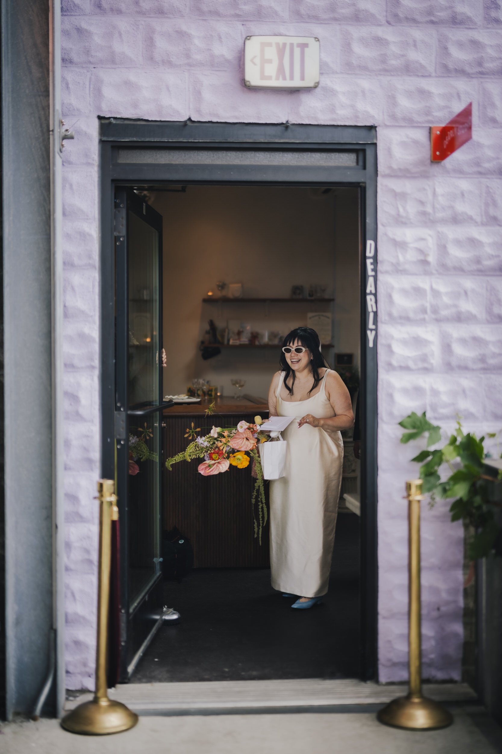  A newlywed in a wedding dress walking out of Dearly Studio 