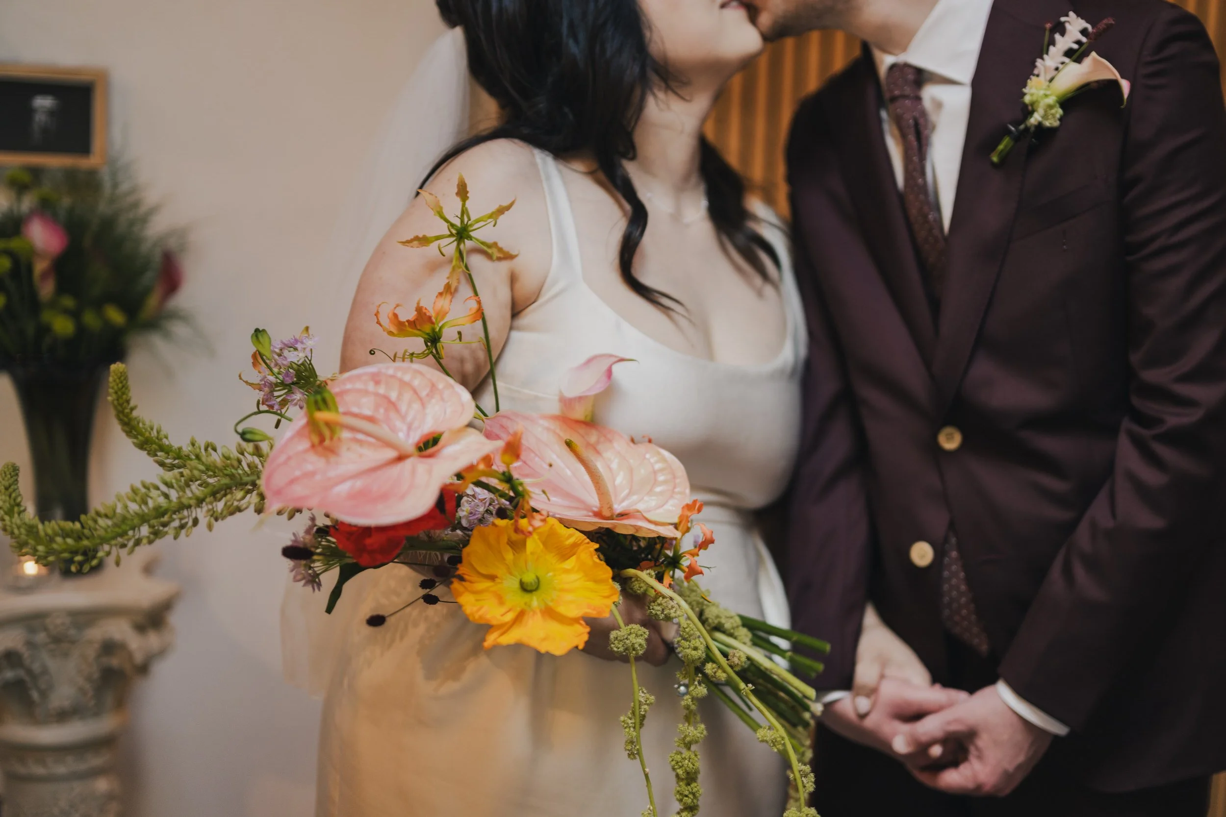  A close up of a newlywed standing next to their partner while holding a bouquet of flowers 