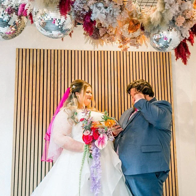 A newlywed wiping a tear away as they stand next to their partner