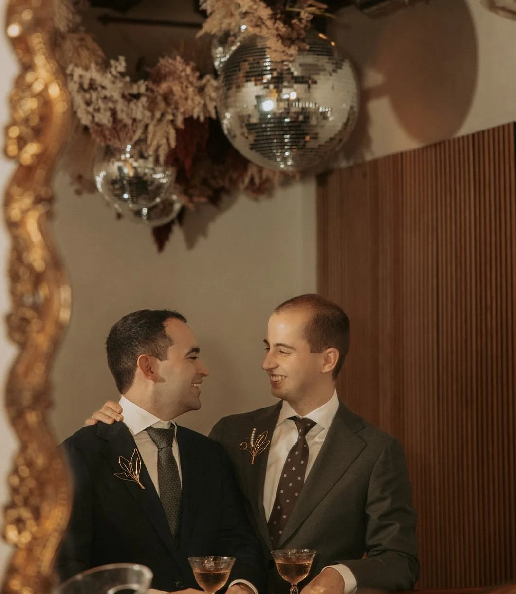 A person with their arm around their partner's shoulder as they smile at each other