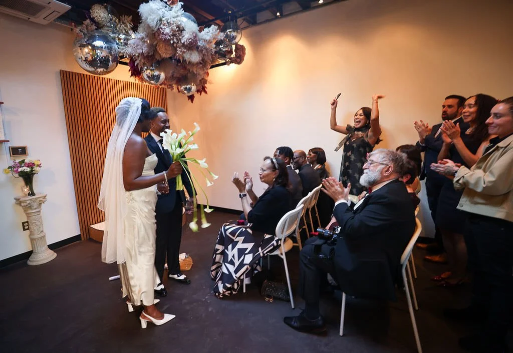 Wedding guests cheering as a newlywed couple walk away from their ceremony