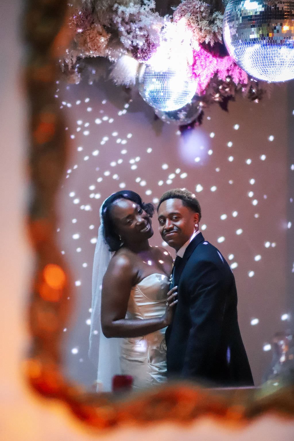  Newlyweds standing close and smiling under disco lights 