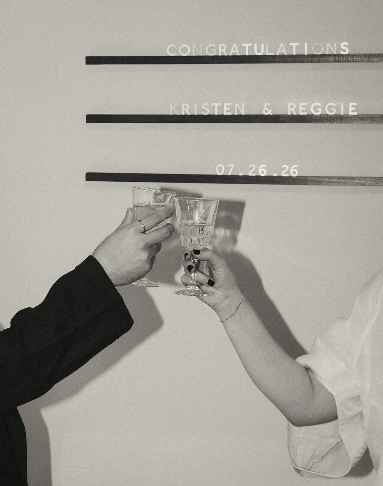 Newlyweds toasting in front of a small sign with their names and wedding date on it  