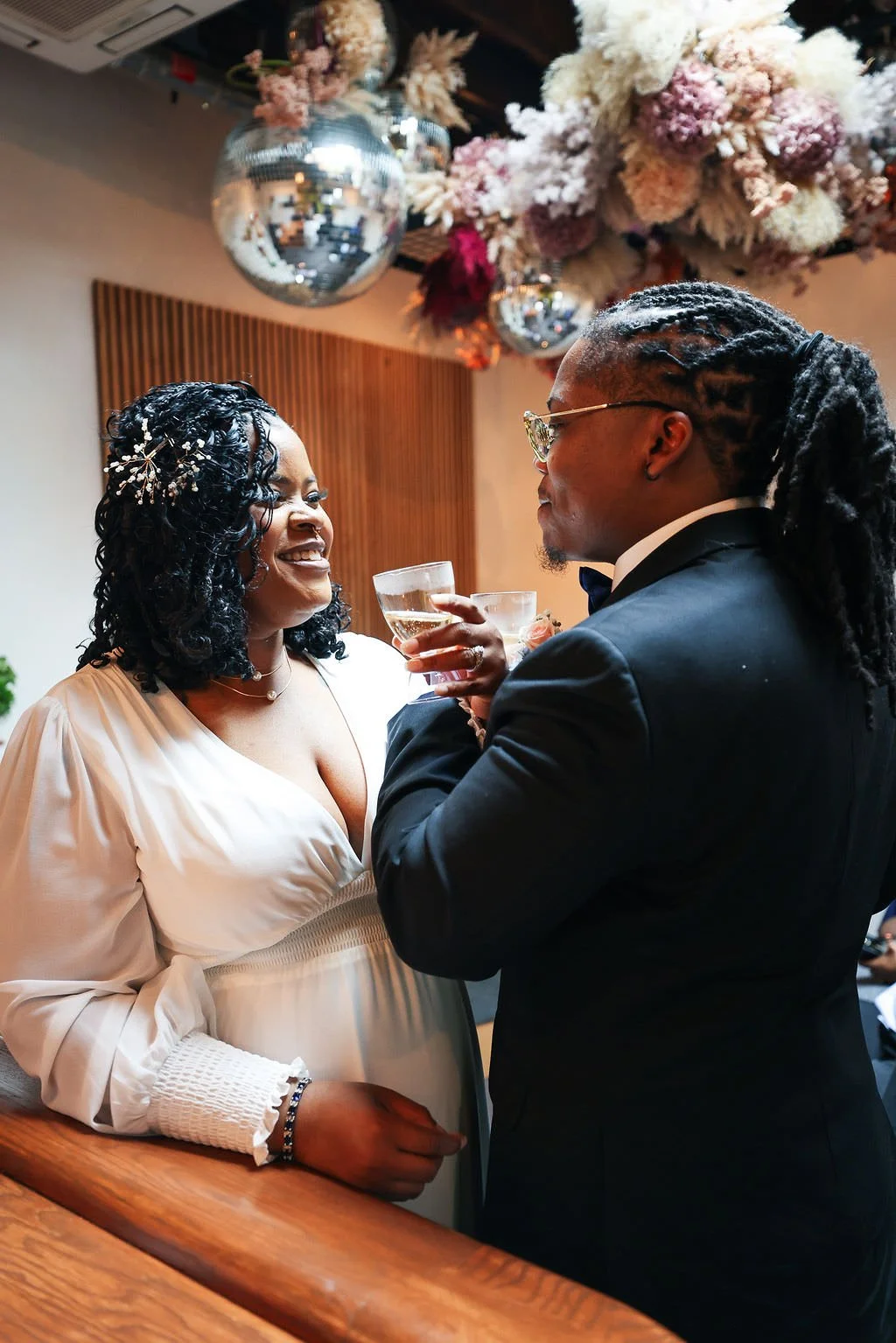 Newlyweds linking arms as they lean in to drink glasses of champagne