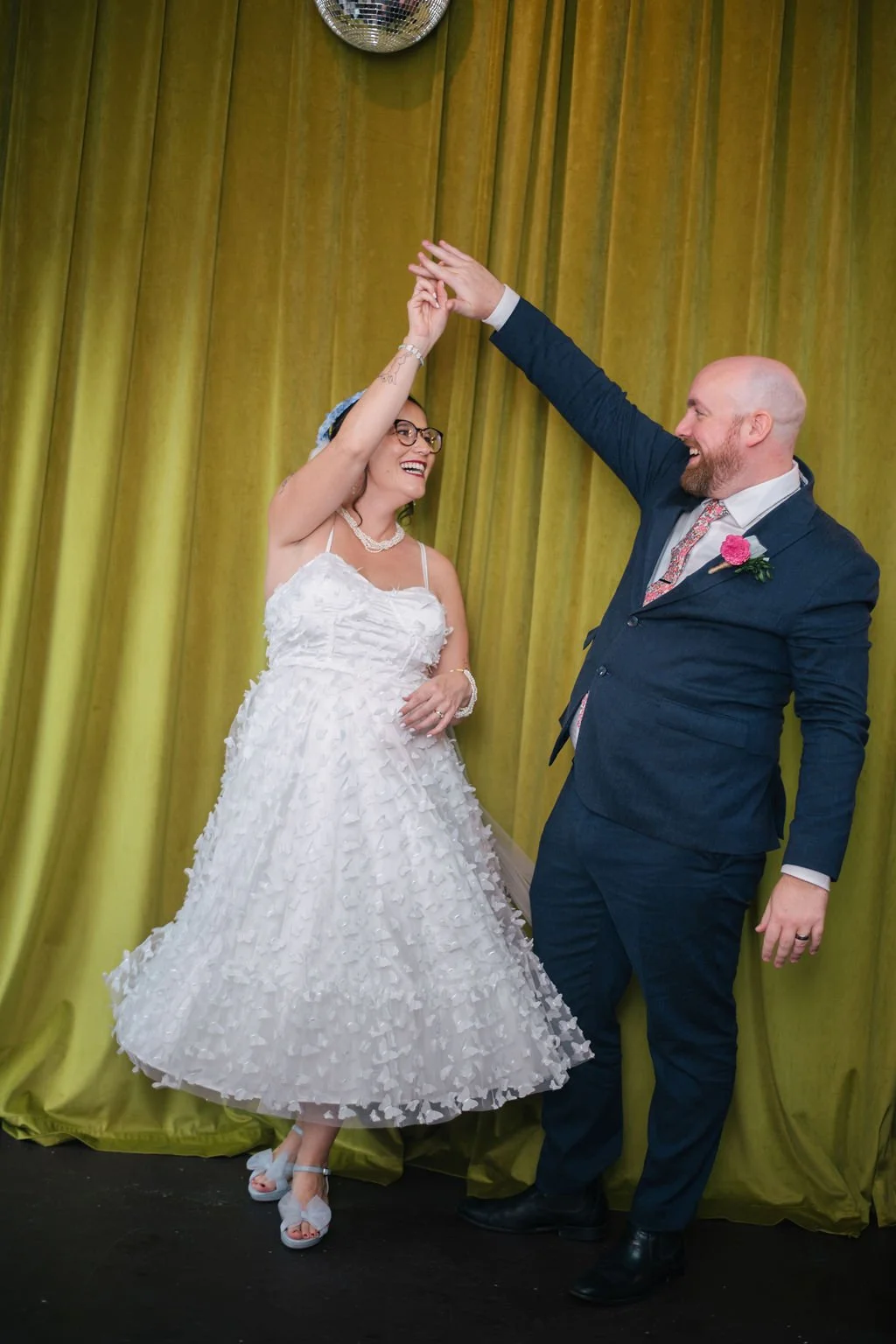 A couple dances on their wedding day in front of a chartreuse-colored backdrop.