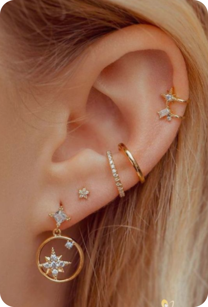 Pin zobrazujúci ženské ucho ozdobené šperkami.