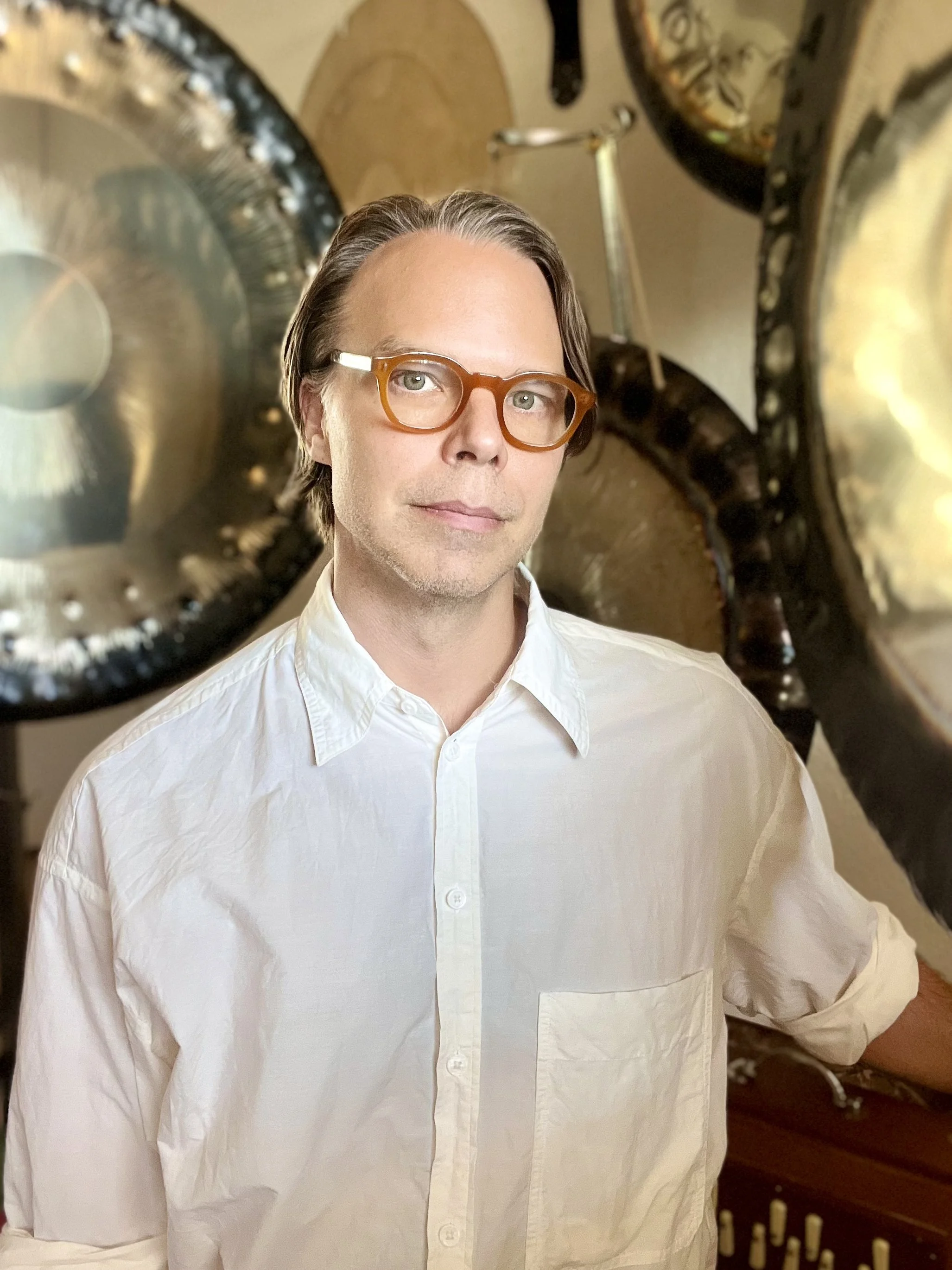 Headshot of ONDO founder Shane Aspegren, in front of large meditation gongs.