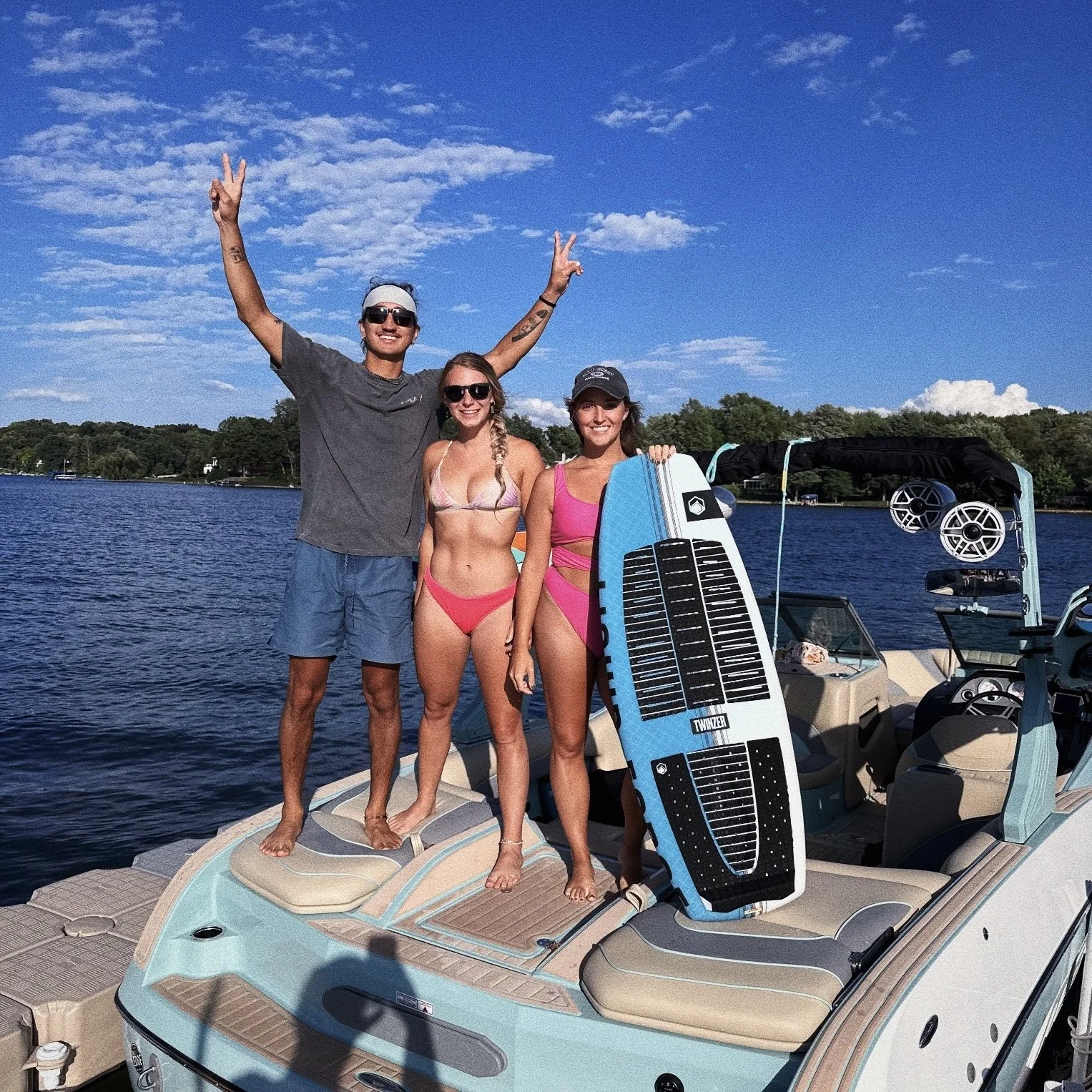 guy and two girls standing on back of wake boat