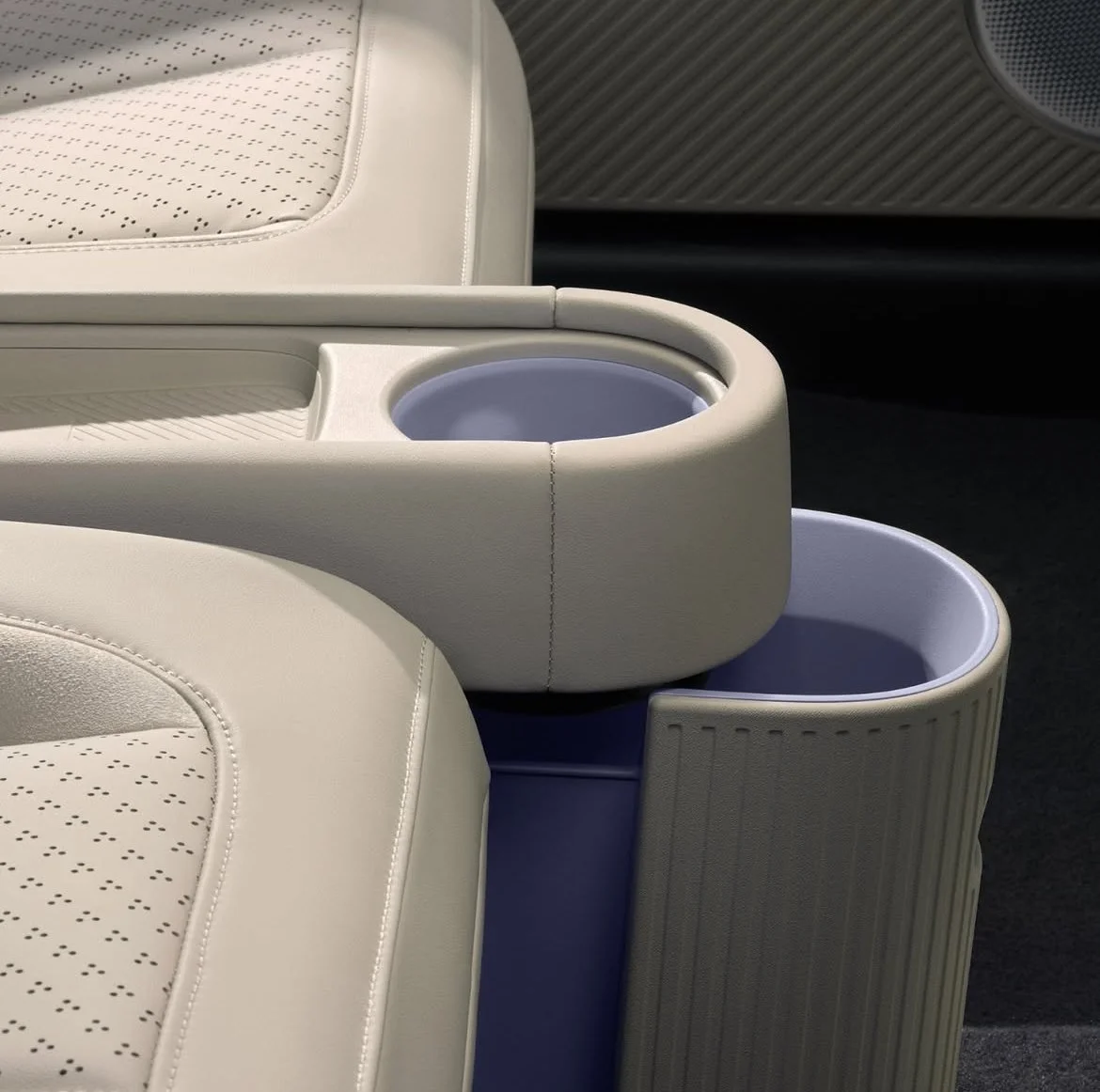 Nahaufnahme von weißen, modernen Sitzmöbeln mit integrierten Bechern und Ablagen in einem Auto.