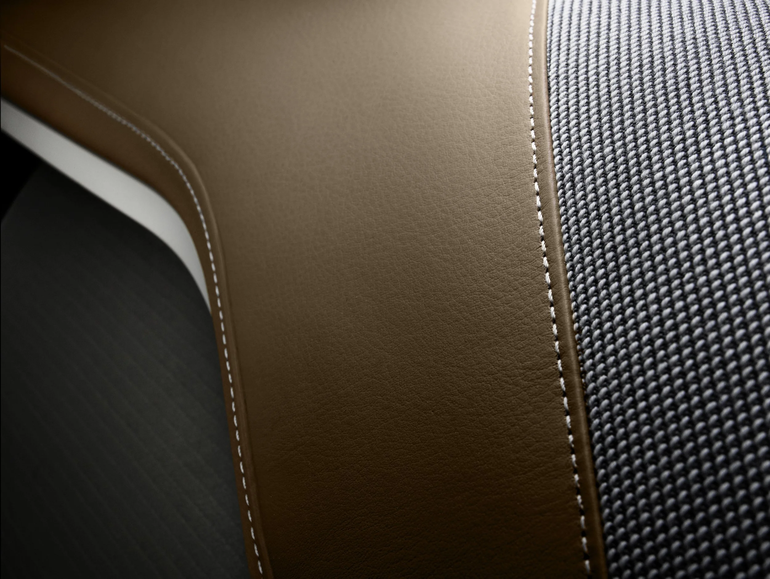 Nahaufnahme eines Stuhls mit braunem Kunstleder und Stoffbezug, hervorgehoben durch weiße Ziernähte.