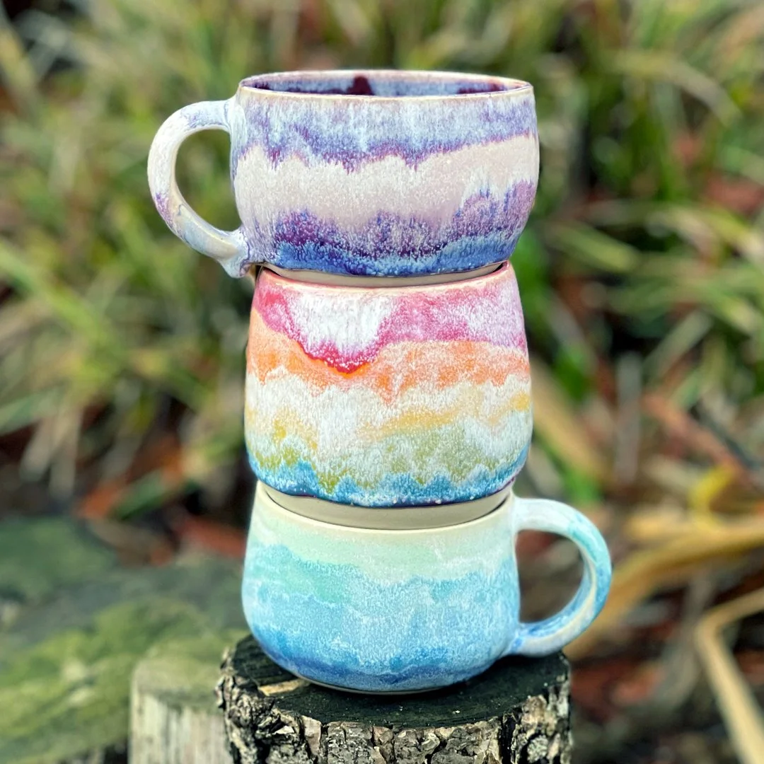 A stack of two mugs and a planter from Stuffed Studio's Rainbow Wave collection. These feature different colors that drip and blend with each other.
