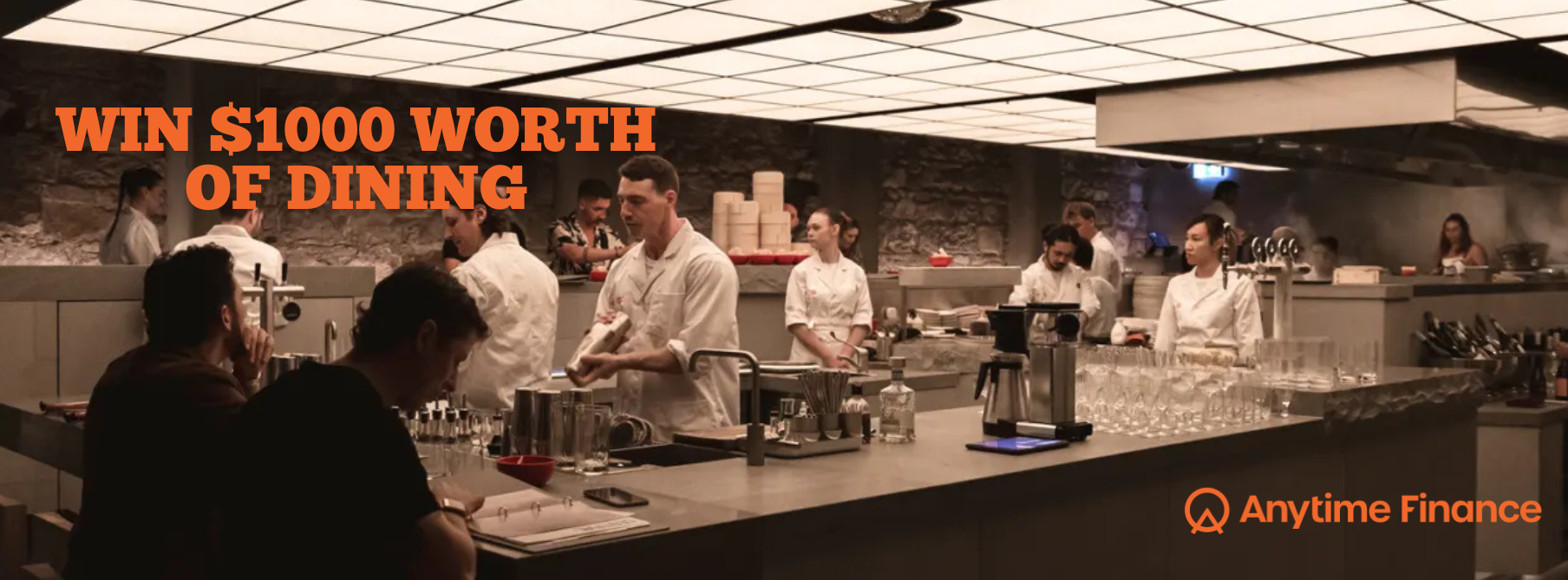 A busy restaurant bar with chefs and staff working behind the counter, and customers sitting at the bar, with promotional text offering a chance to win $1000 worth of dining from Anytime Finance.